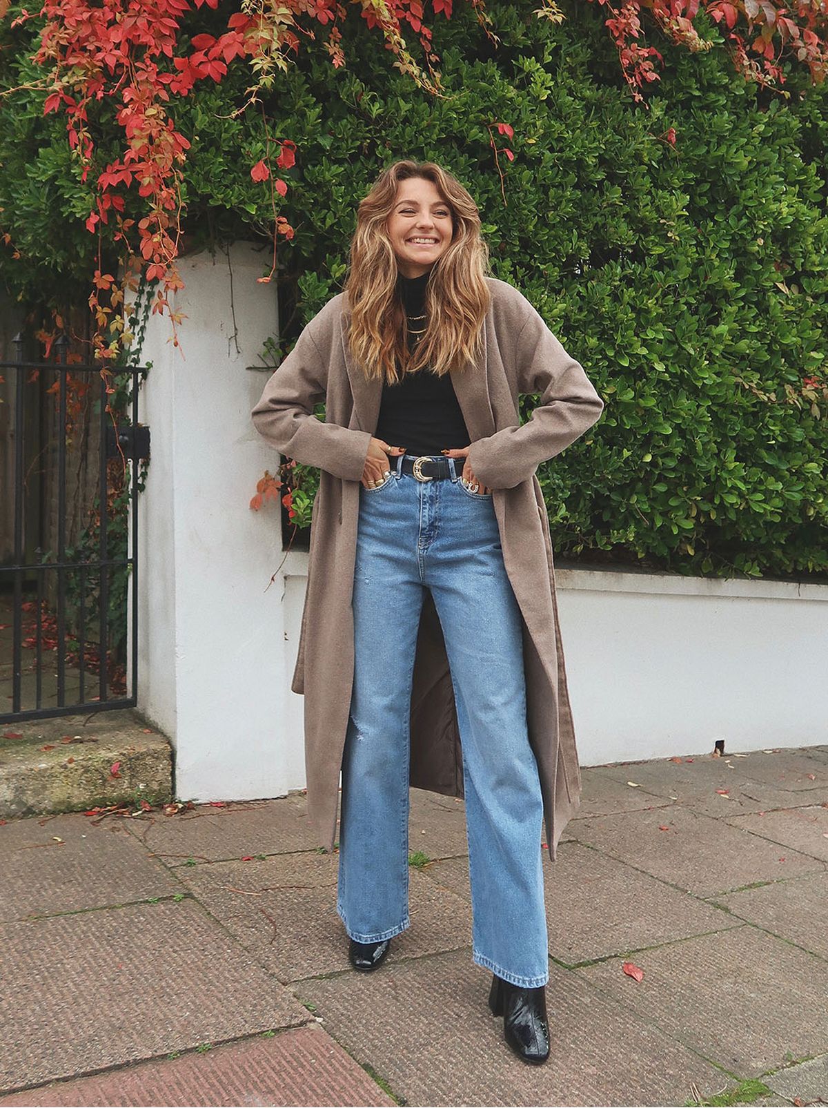 woman wearing mink maxi coat, wide-leg jeans and black roll-neck jumper