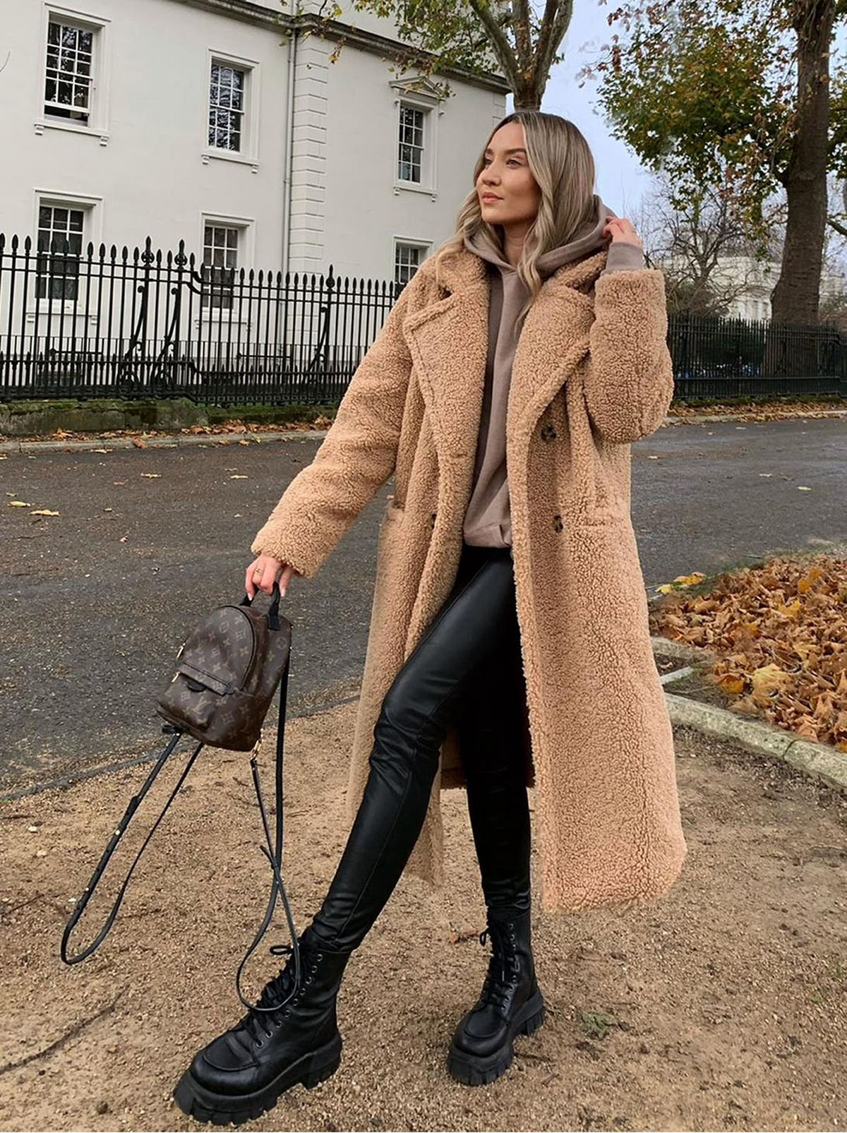 woman walking on the street, wearing stone teddy coat, leather trouser, beige hoodie