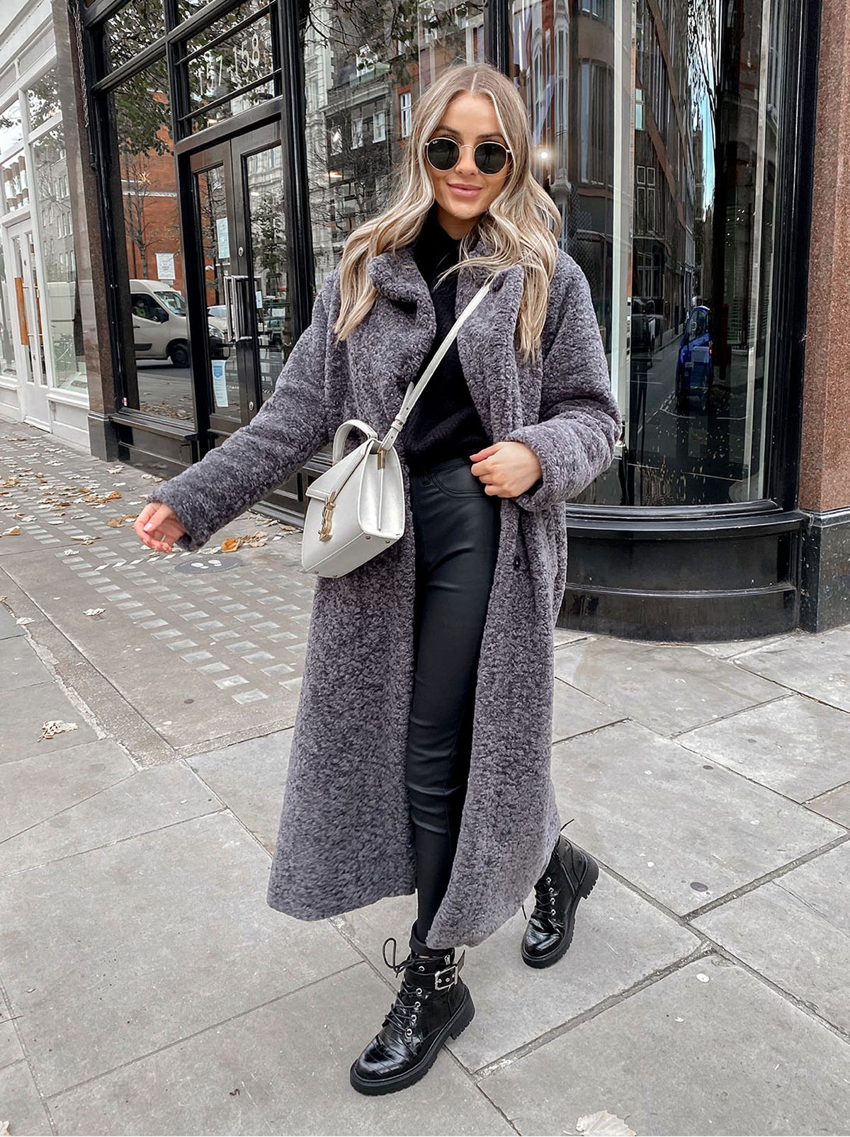 woman wearing grey faux fur maxi coat, coated jeans and black jumper