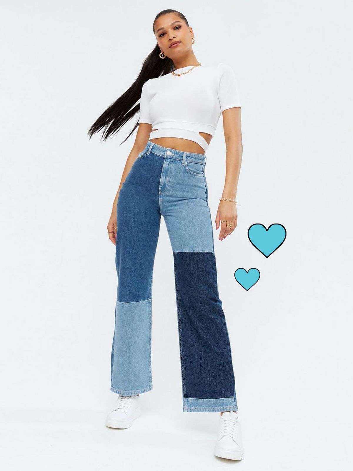 Woman wearing blue patchwork high waist wide leg jeans, white top and trainers