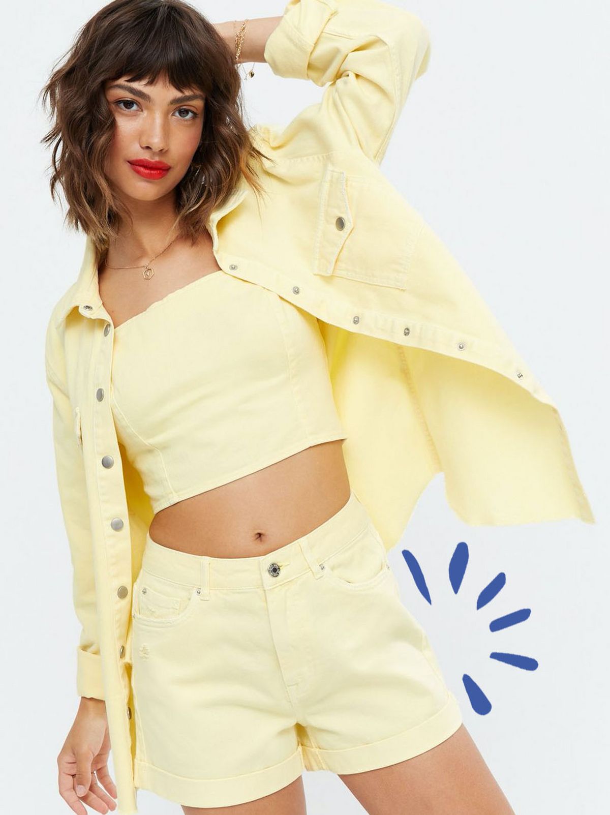 Woman wearing a yellow denim oversized shirt, yellow denim shorts and yellow crop top