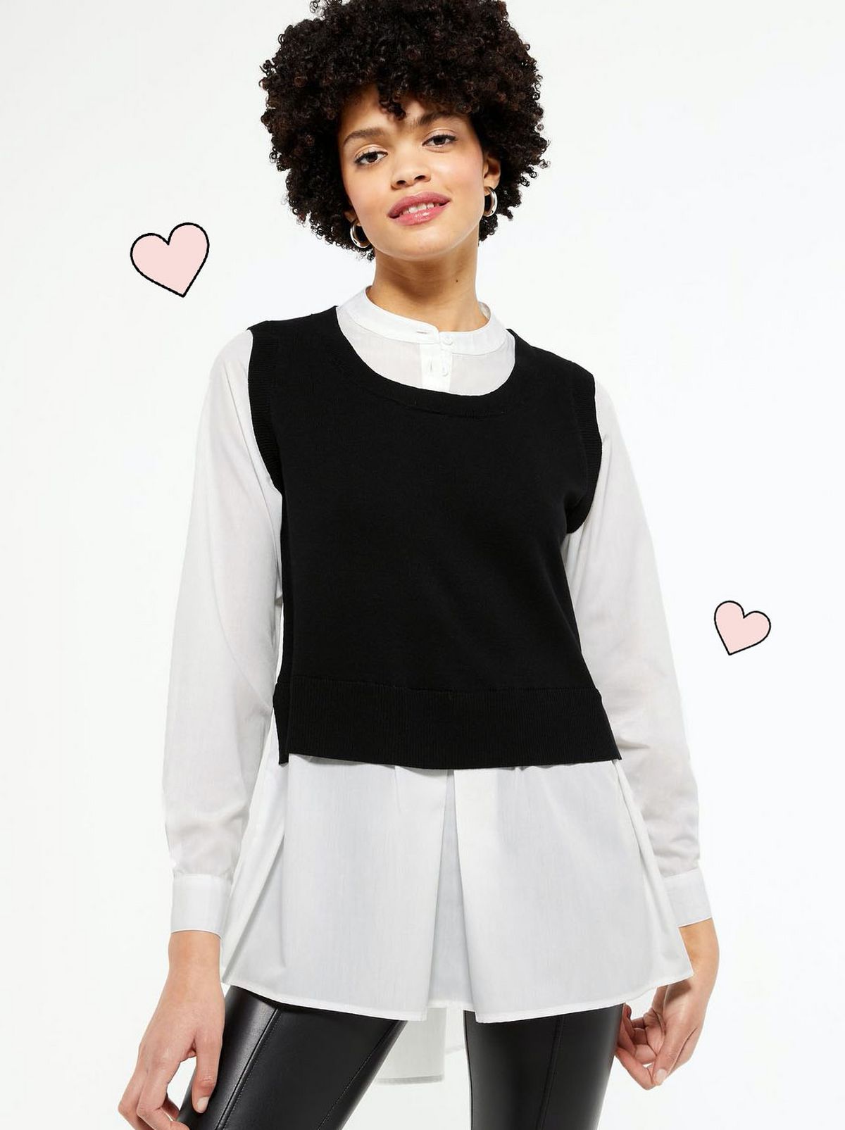 Woman wearing along sleeve white shirt, black jumper and black leather look trousers