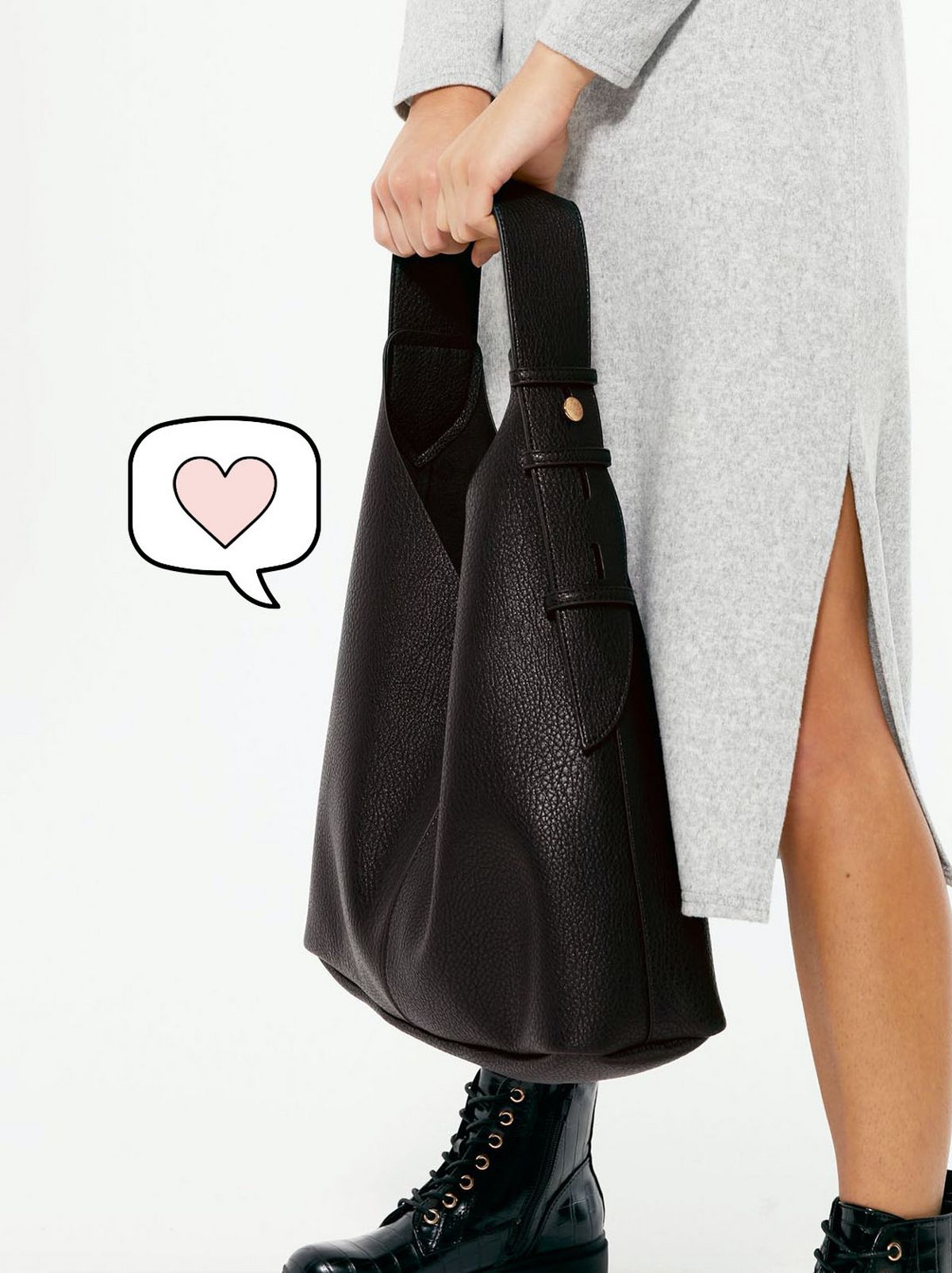 Woman wearing a long grey dress, black ankle boots and holding a black leather look tote bag