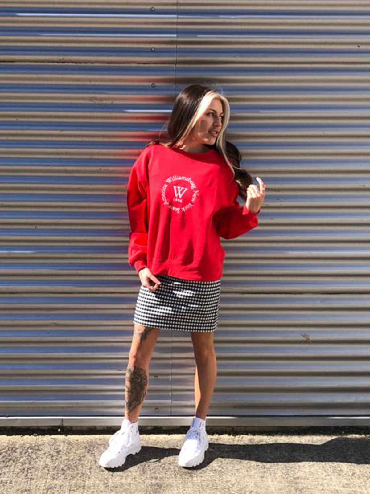 Jessica Croston, Supervisor at New Look Swindon wearing a red jumper, black and white checked skirt and white chunky trainers