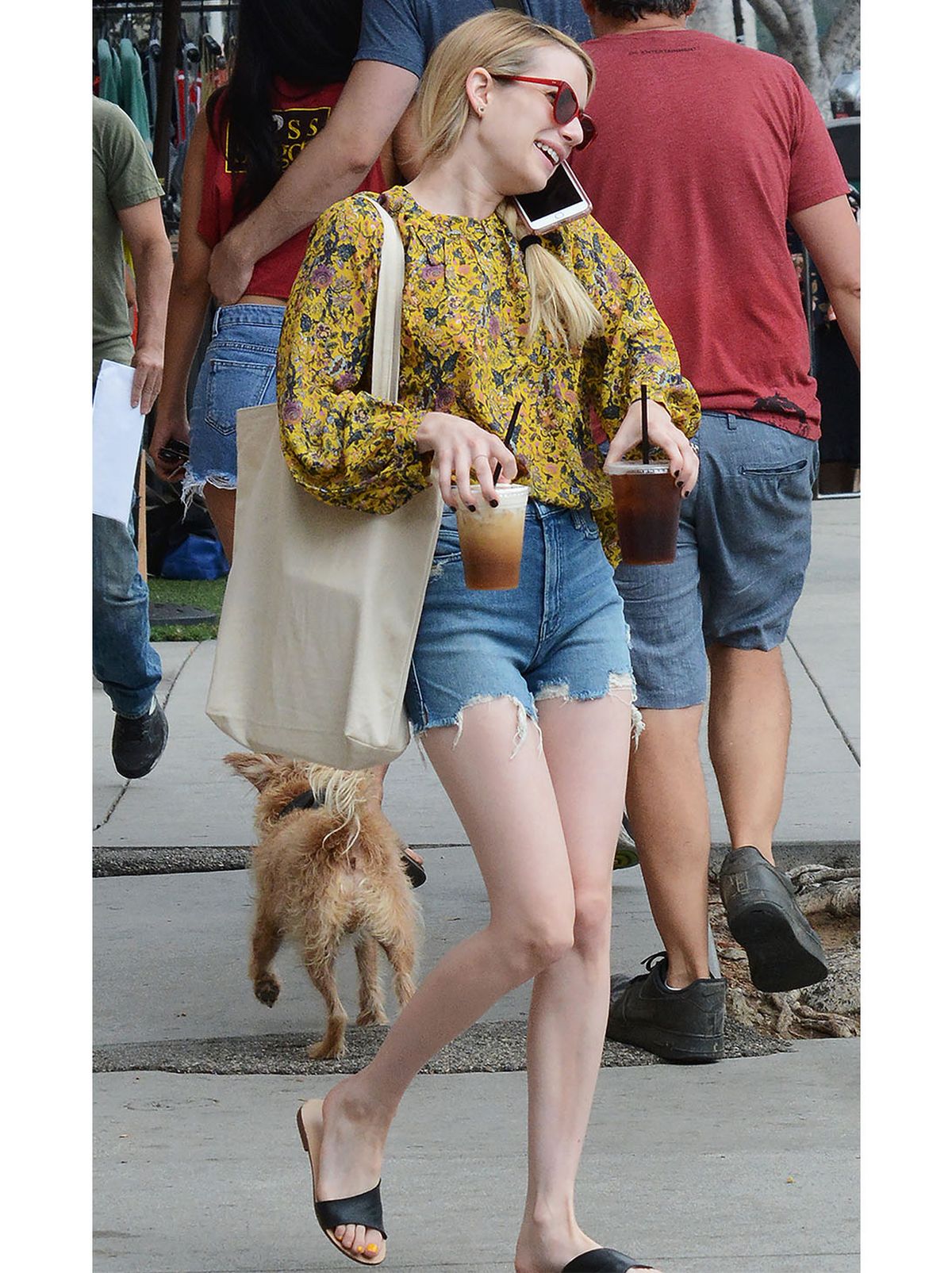 Emma Roberts wearing blue denim shorts, floral printed top and sliders