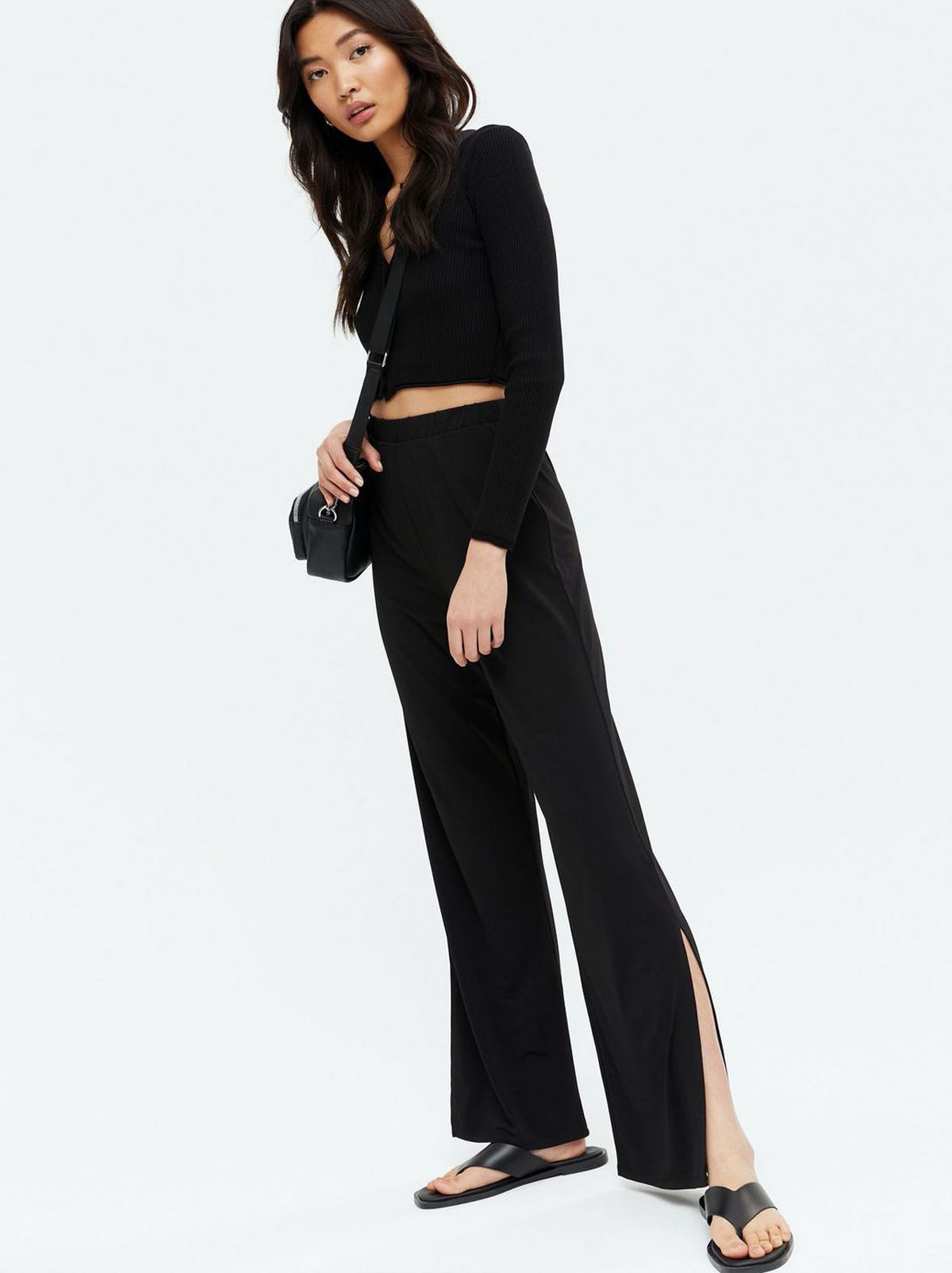 Woman wearing a black high waist side split trousers and black top
