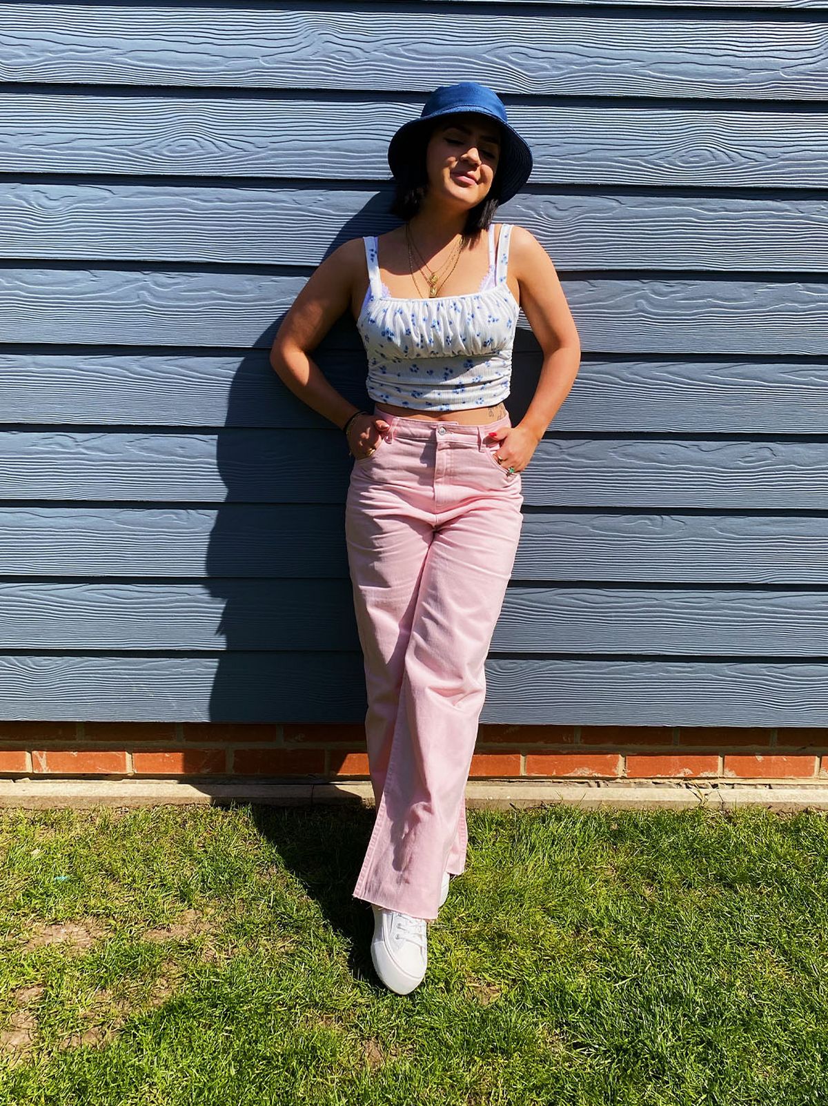 Chessie Lulli wearing a floral crop top, pink jeans, hat and trainers