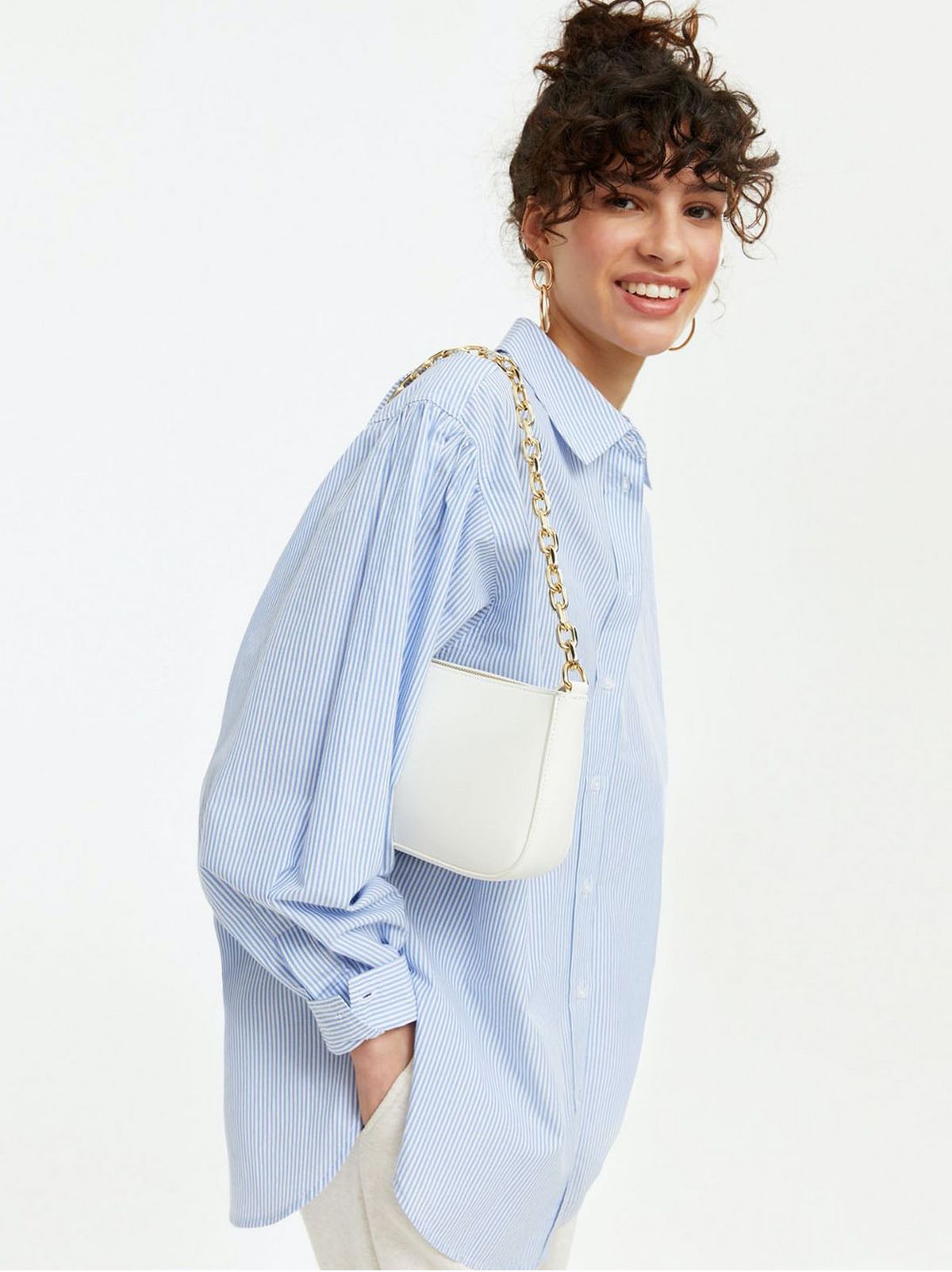 Woman wearing a blue shirt with a white chain shoulder bag