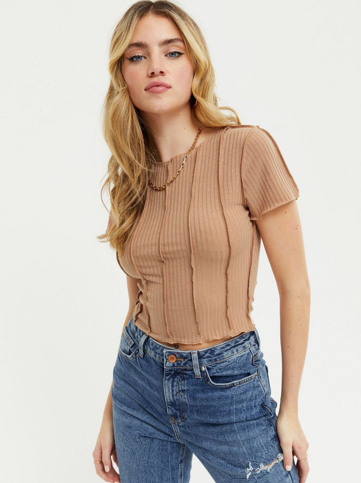 Woman wearing a camel ribbed seam t-shirt and blue jeans