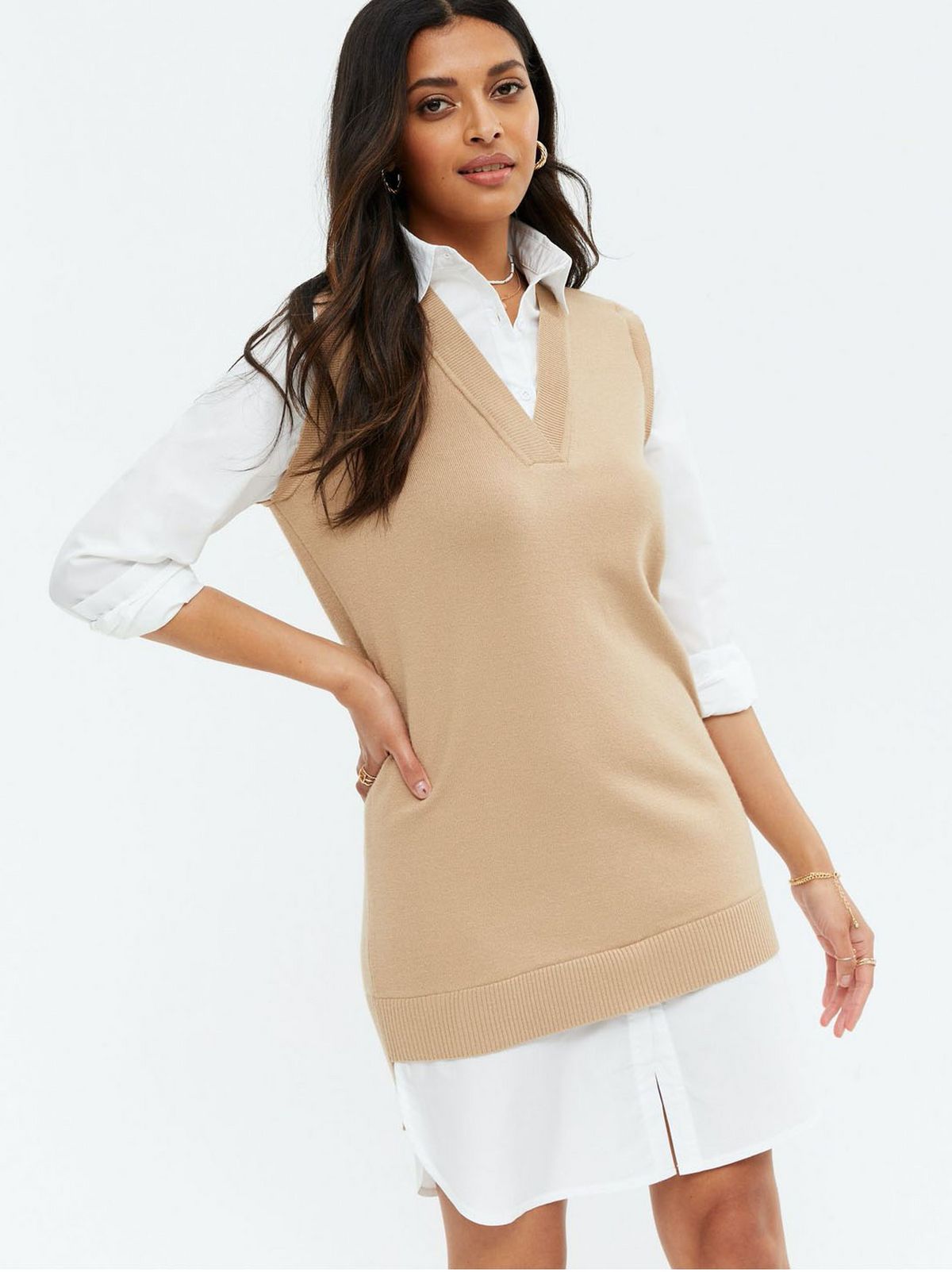 Woman wearing a camel vest and white shirt dress