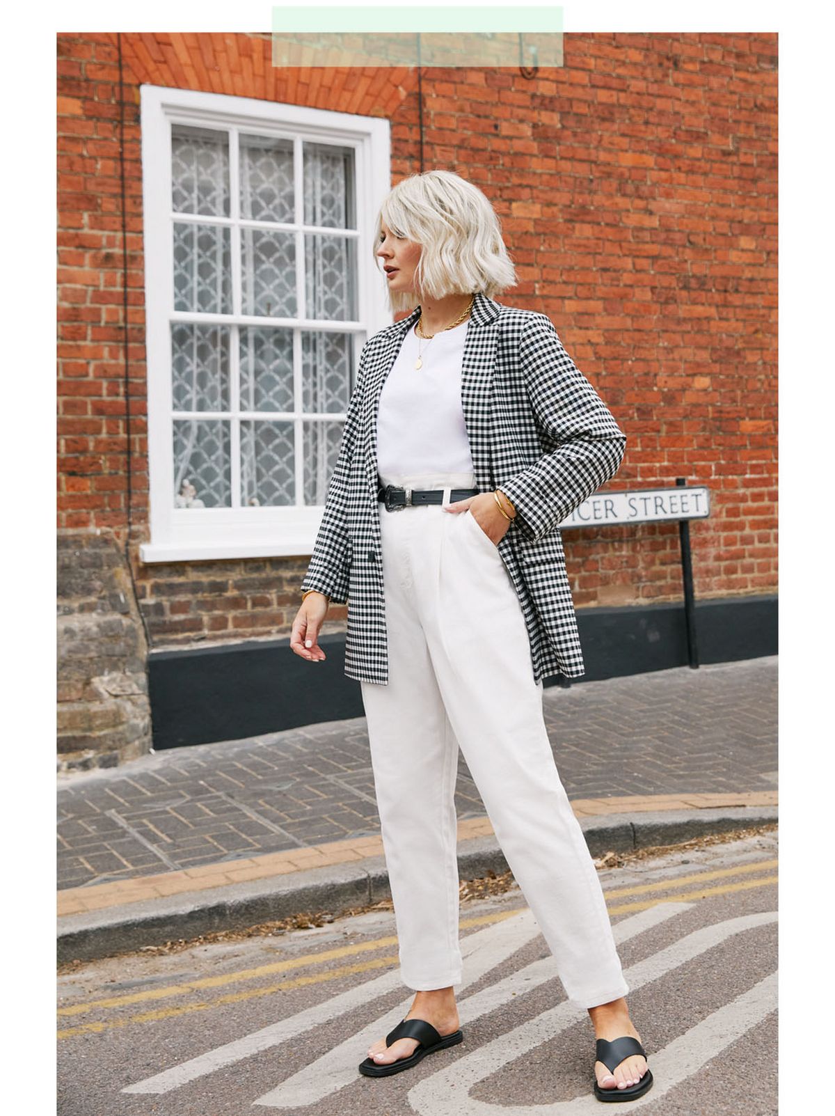 Laura B wearing a black gingham blazer, white tshirt, white cropped trousers and black sandals.