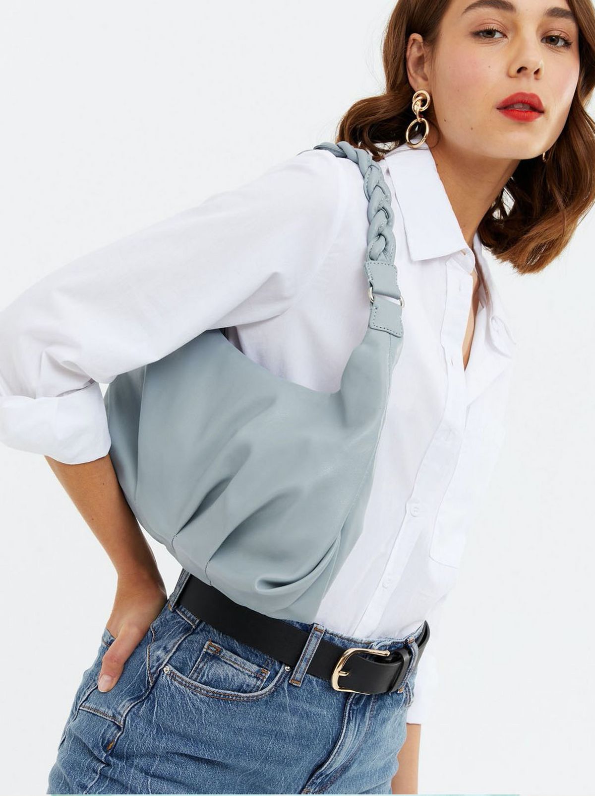 Woman wearing a Blue Leather Look Plaited Strap Shoulder Bag, white shirt and blue jeans