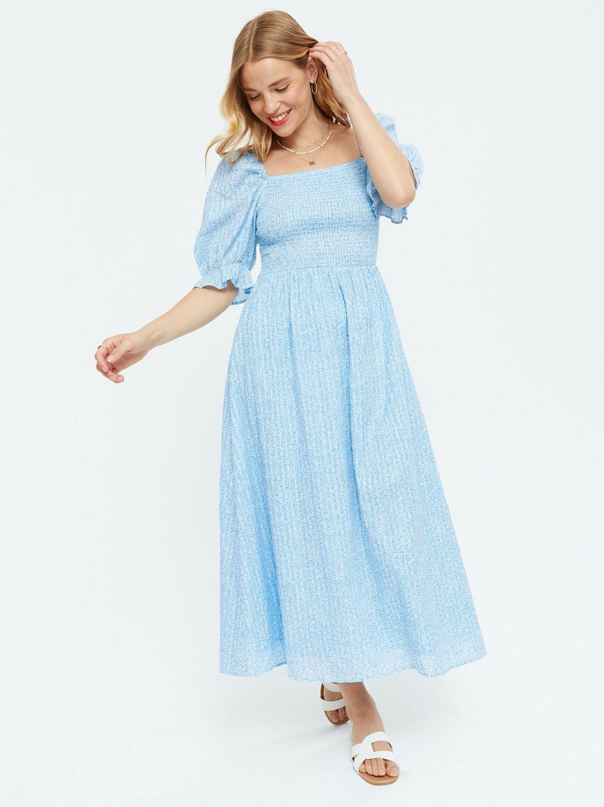 Woman wearing a Blue Ditsy Floral Shirred Puff Sleeve Midi Dress and white sliders
