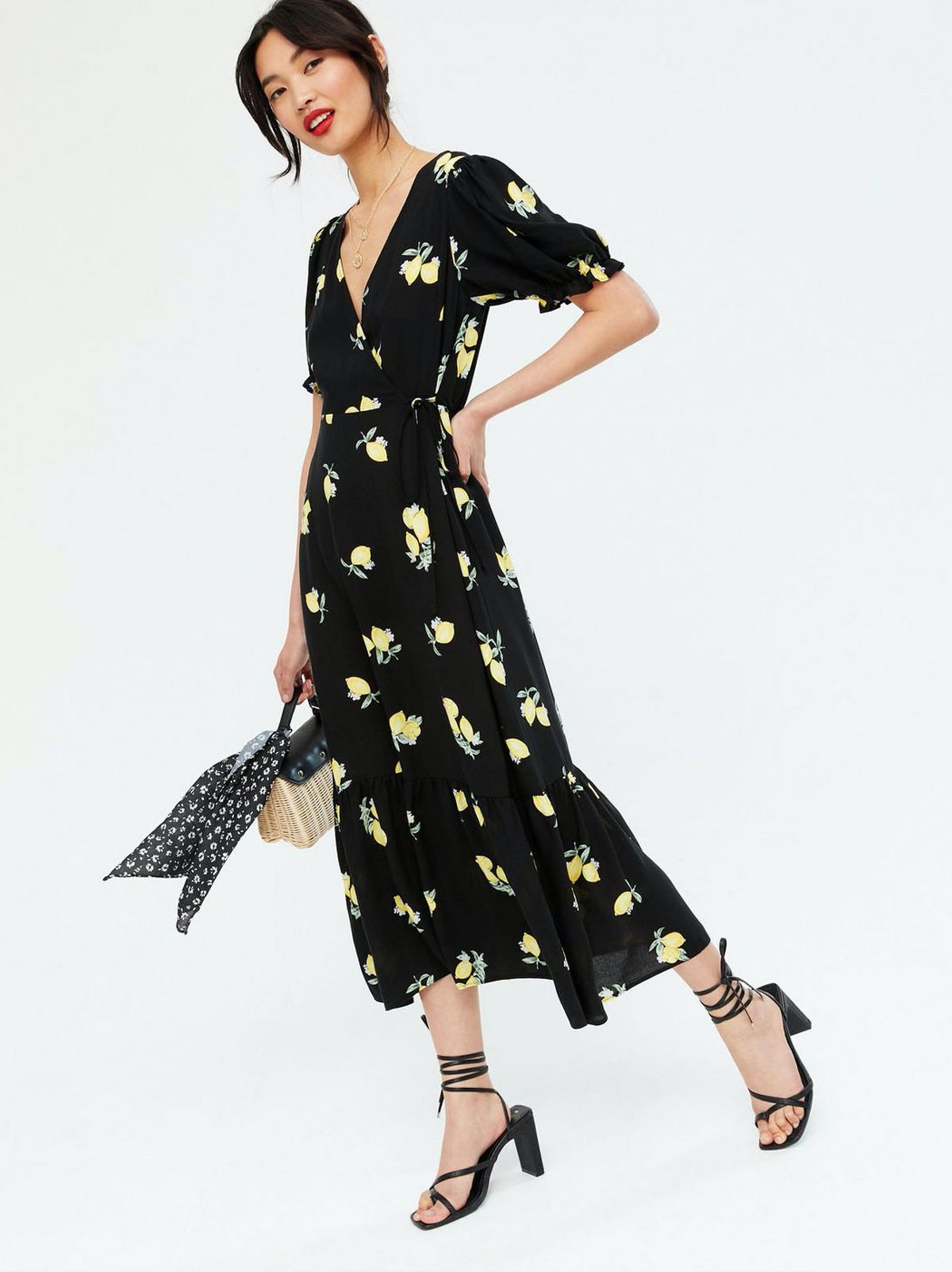 Woman wearing a Black Lemon Tiered Wrap Midi Dress and black strappy heels