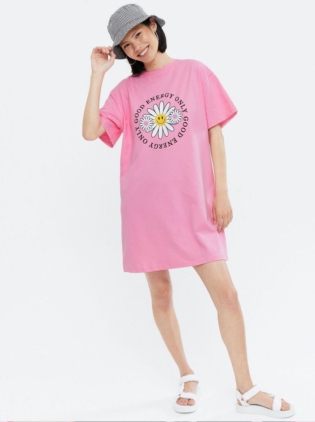 Woman wearing a Pink Floral Good Energy Logo T Shirt Dress, bucket hat and white sandals