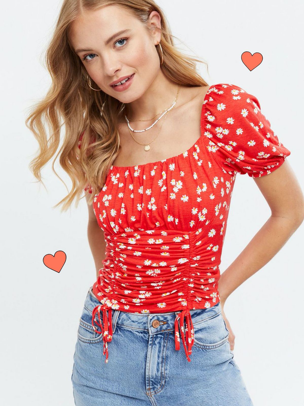 Woman wearing a red daisy puff sleeve top and blue jeans