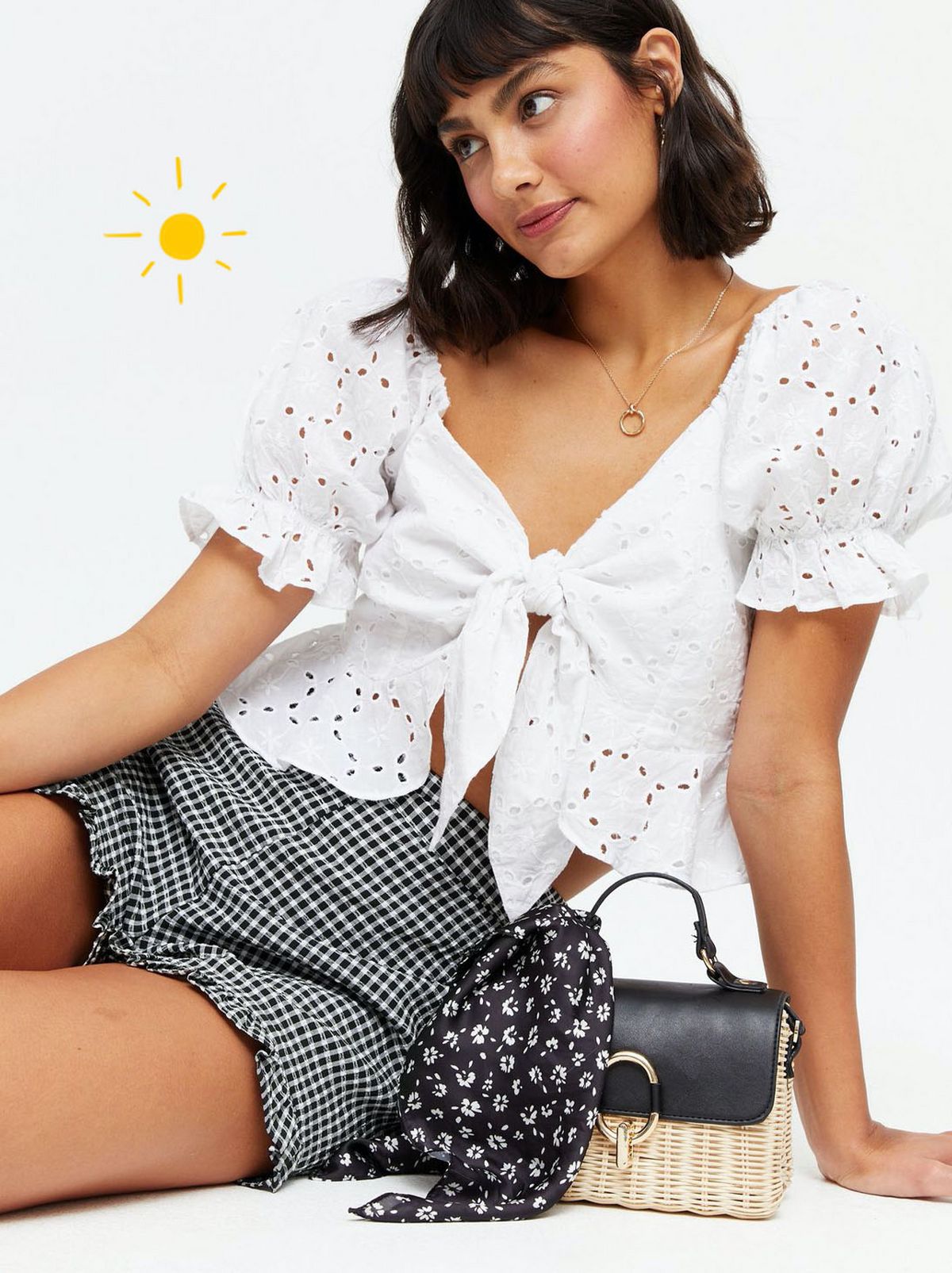 Woman wearing a black gingham high waist frill shorts and white tie front blouse