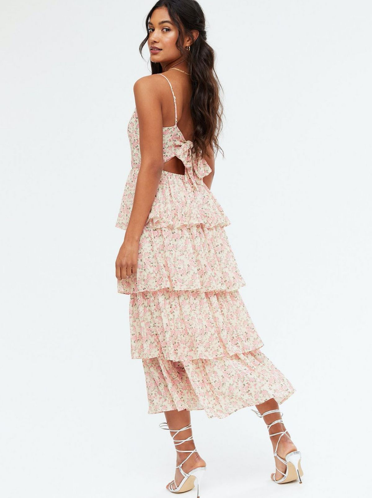 Woman wearing a pink ditsy floral tiered tie back midi dress and strappy heels