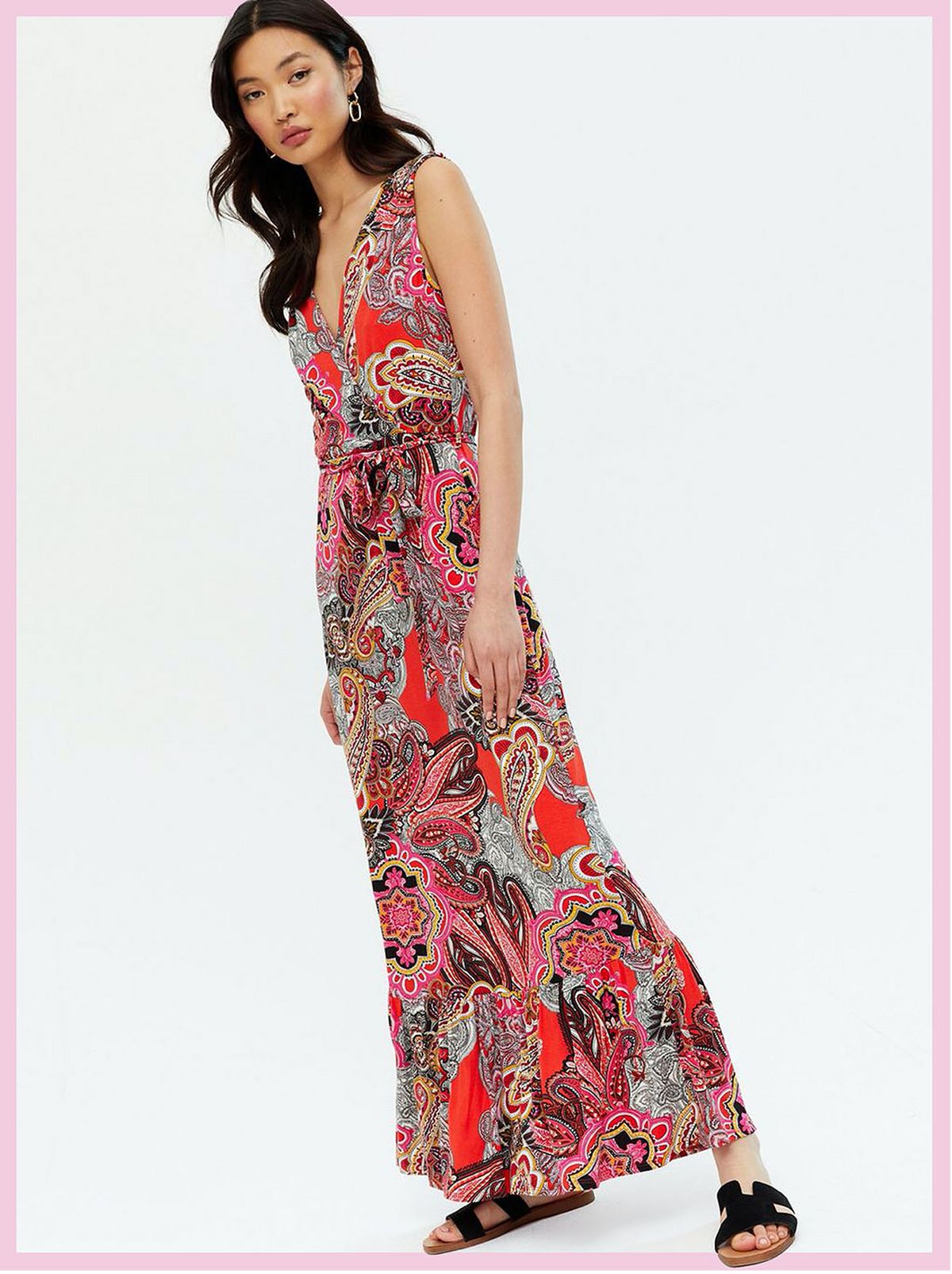 Woman wearing a orange paisley tiered wrap maxi dress and sandals