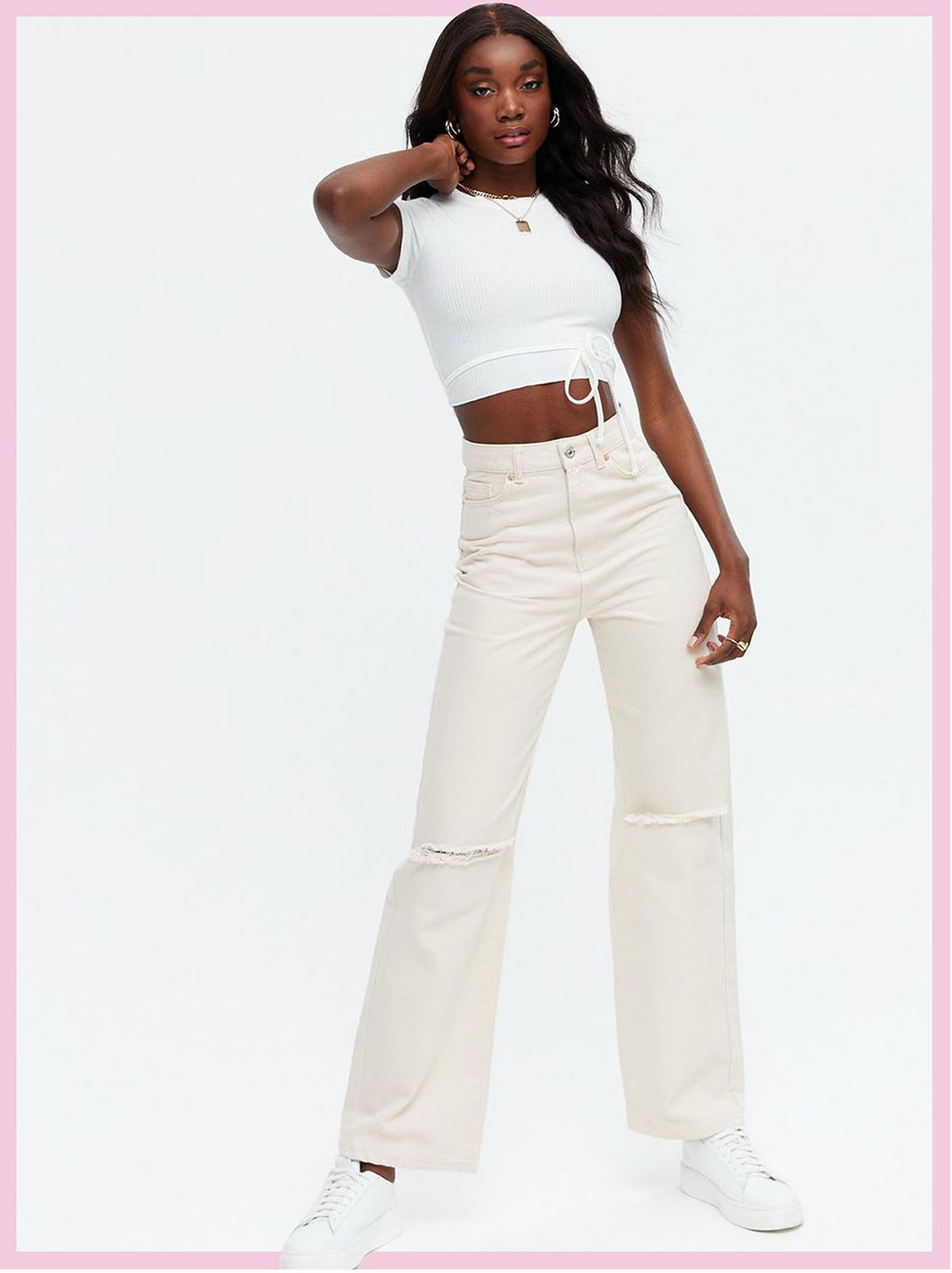 Woman wearing off white ripped 90s baggy fit jeans and white top with trainers