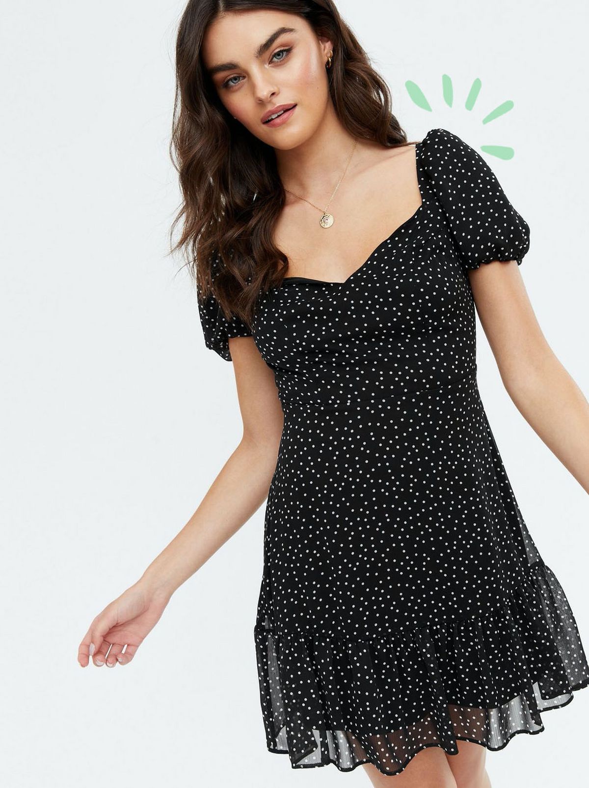 Woman wearing a black spot chiffon open back mini dress