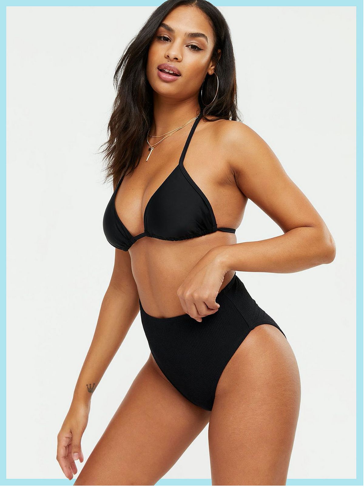 Woman wearing a black textured high waisted bikini bottoms and matching top