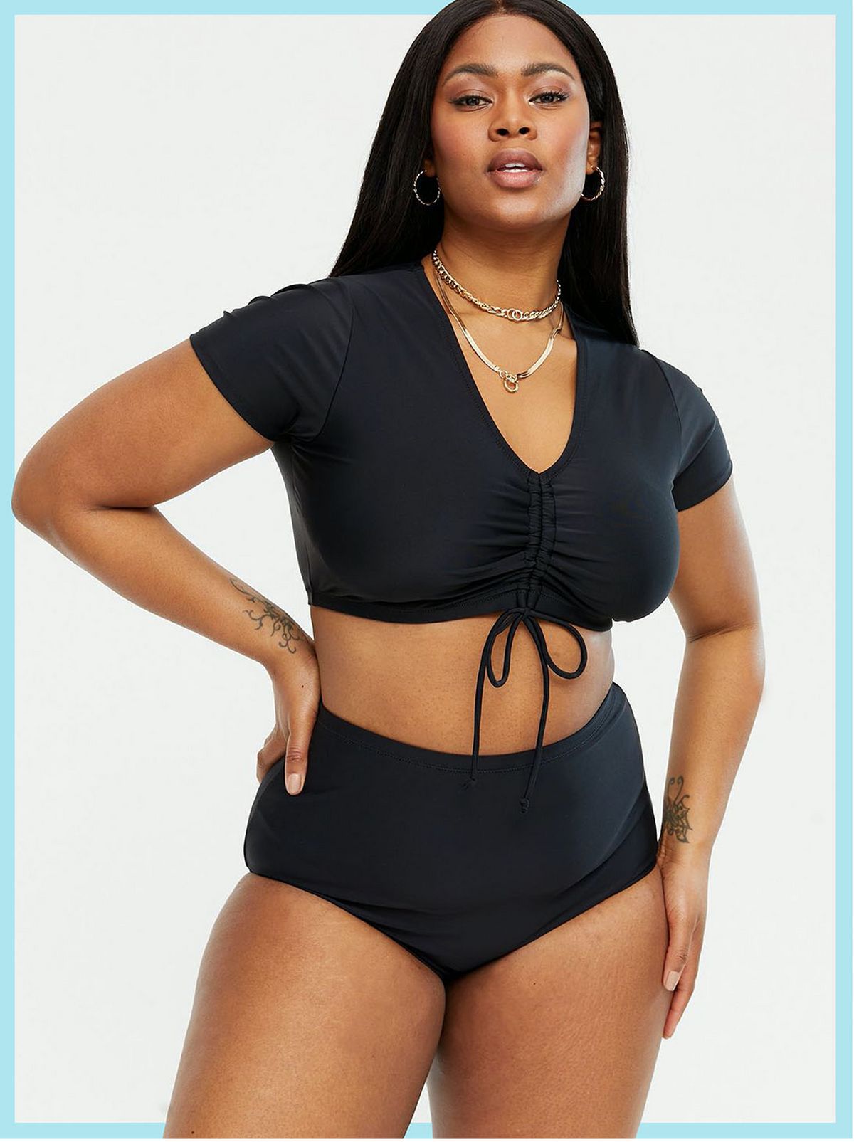 Woman wearing a black cap sleeve ruched tie bikini top and matching black bottoms