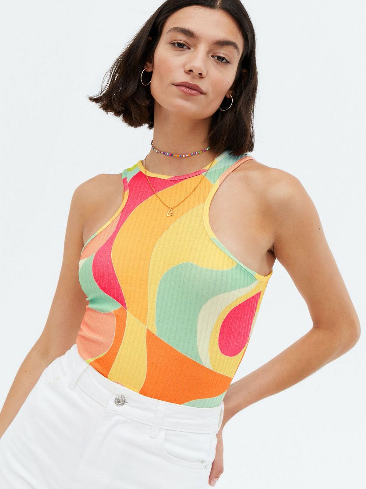 Woman wearing a multicoloured abstract ribbed racer vest and white jeans