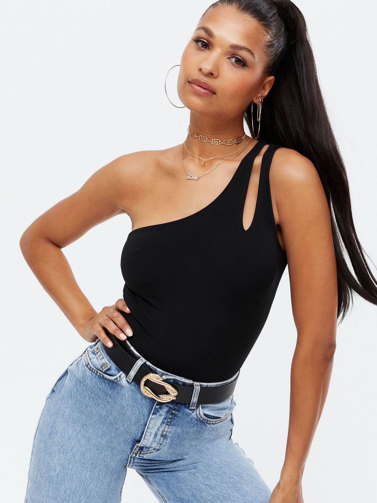 Woman wearing a black cut out one shoulder bodysuit and blue jeans