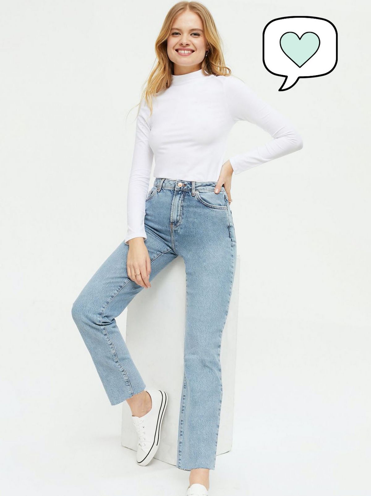 Woman wearing blue vintage wash straight leg jeans, white trainers and long sleeve top
