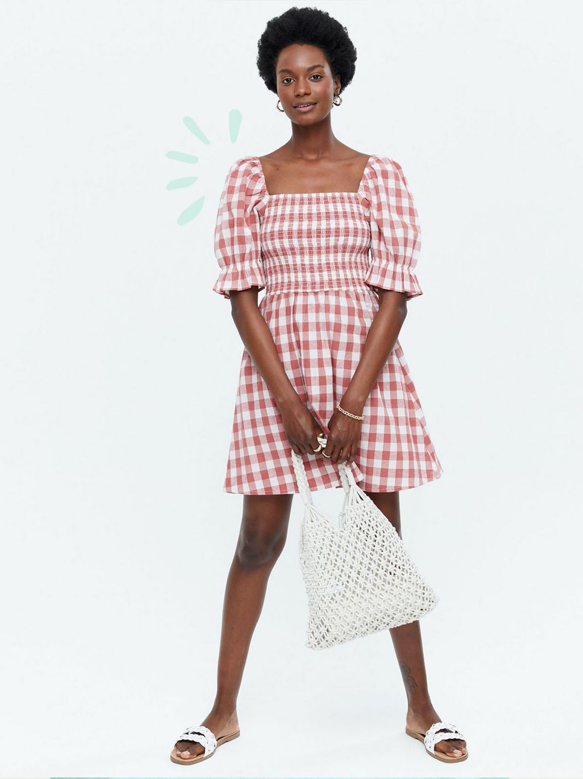Woman wearing a red gingham shirred mini dress and white sliders
