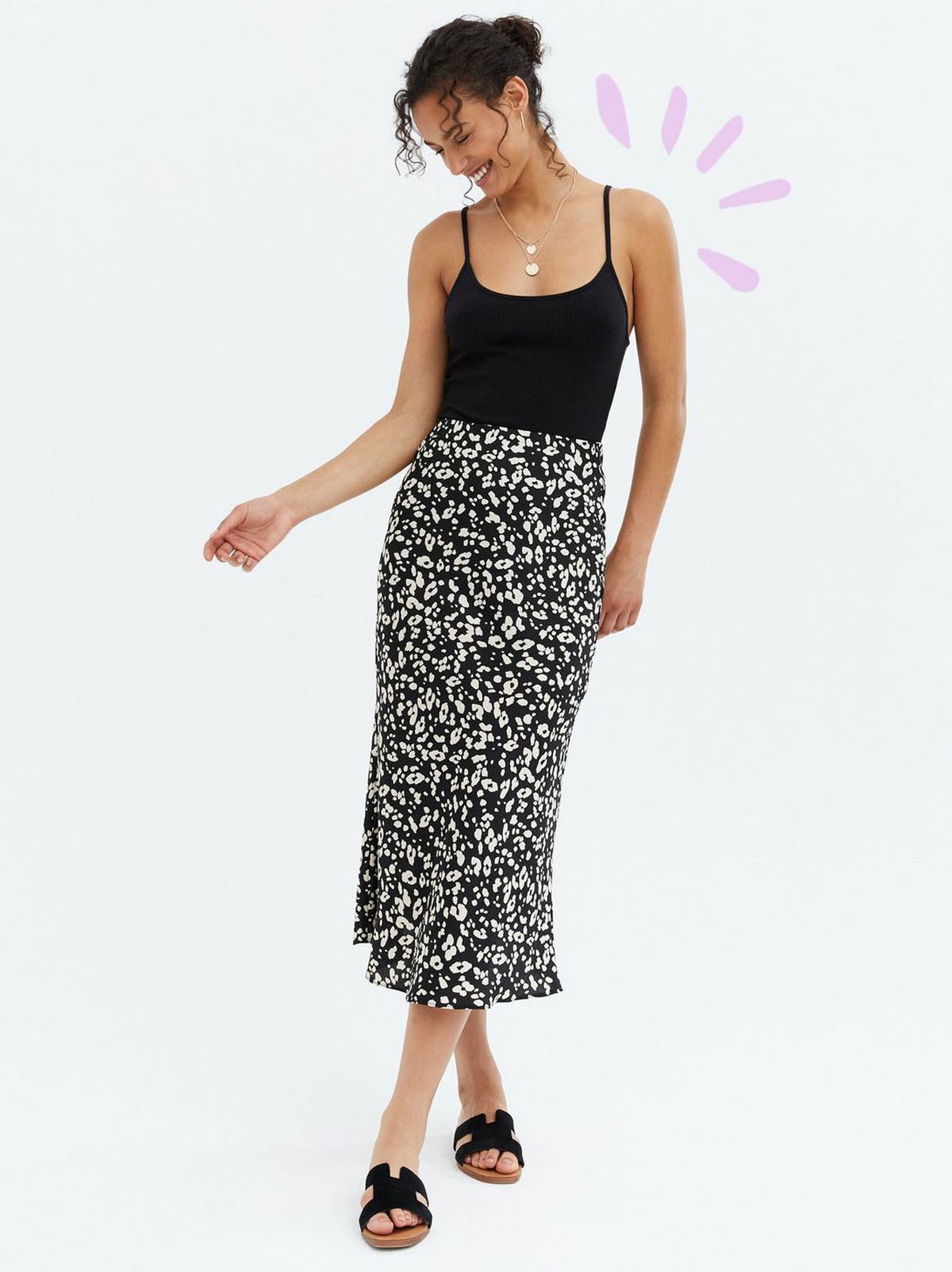 Woman wearing a black animal print midi skirt, black vest top and sandals
