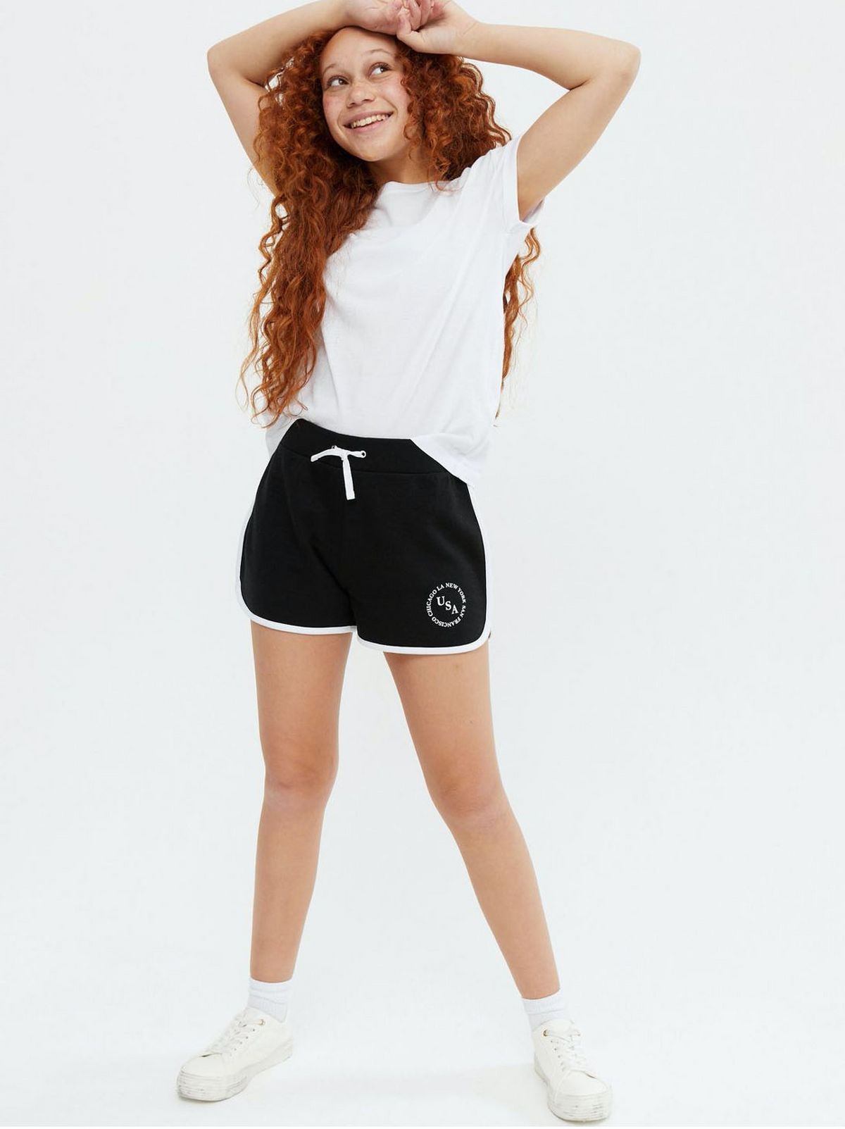 Girl wearing black USA logo runner shorts and white t-shirt