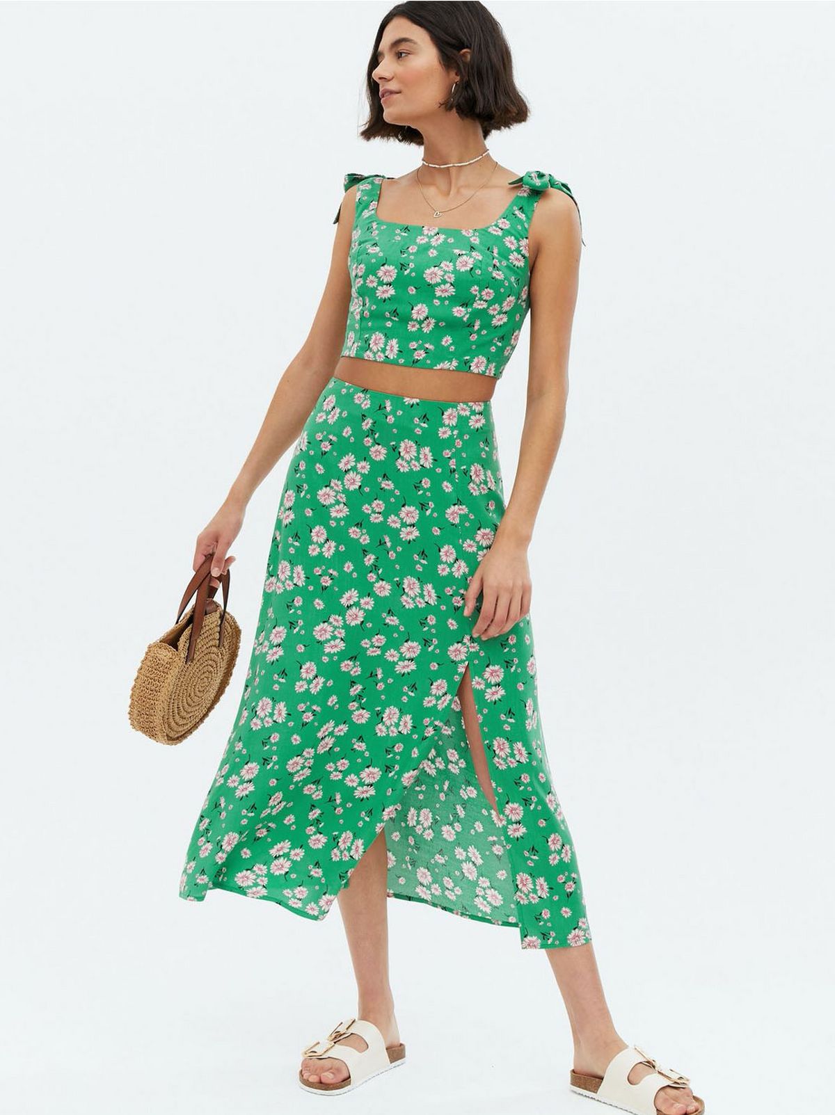 Woman wearing a green daisy high waist midi skirt, matching crop top and sandals