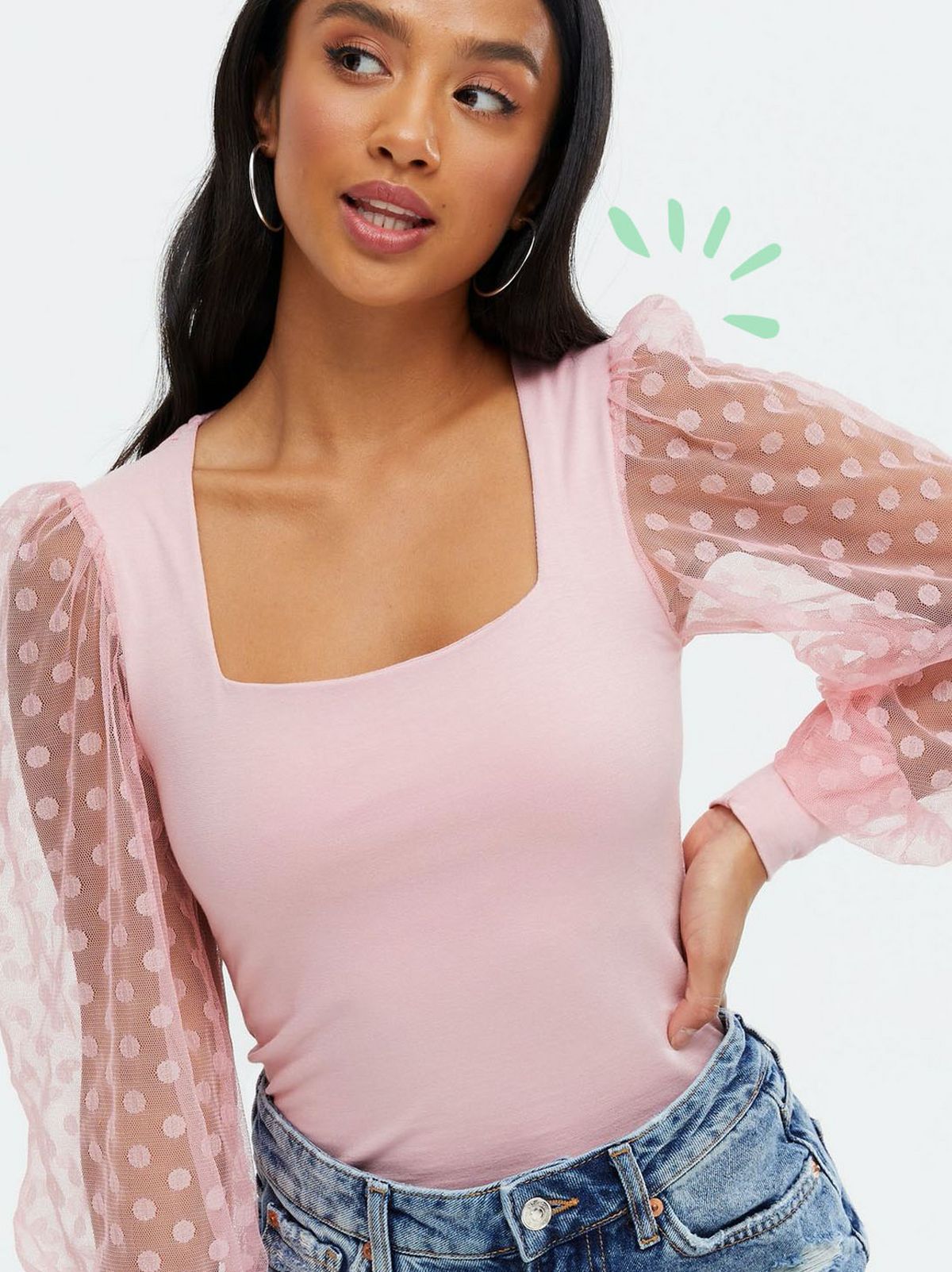 Woman wearing a pale pink spot mesh puff sleeve square neck top and blue jeans
