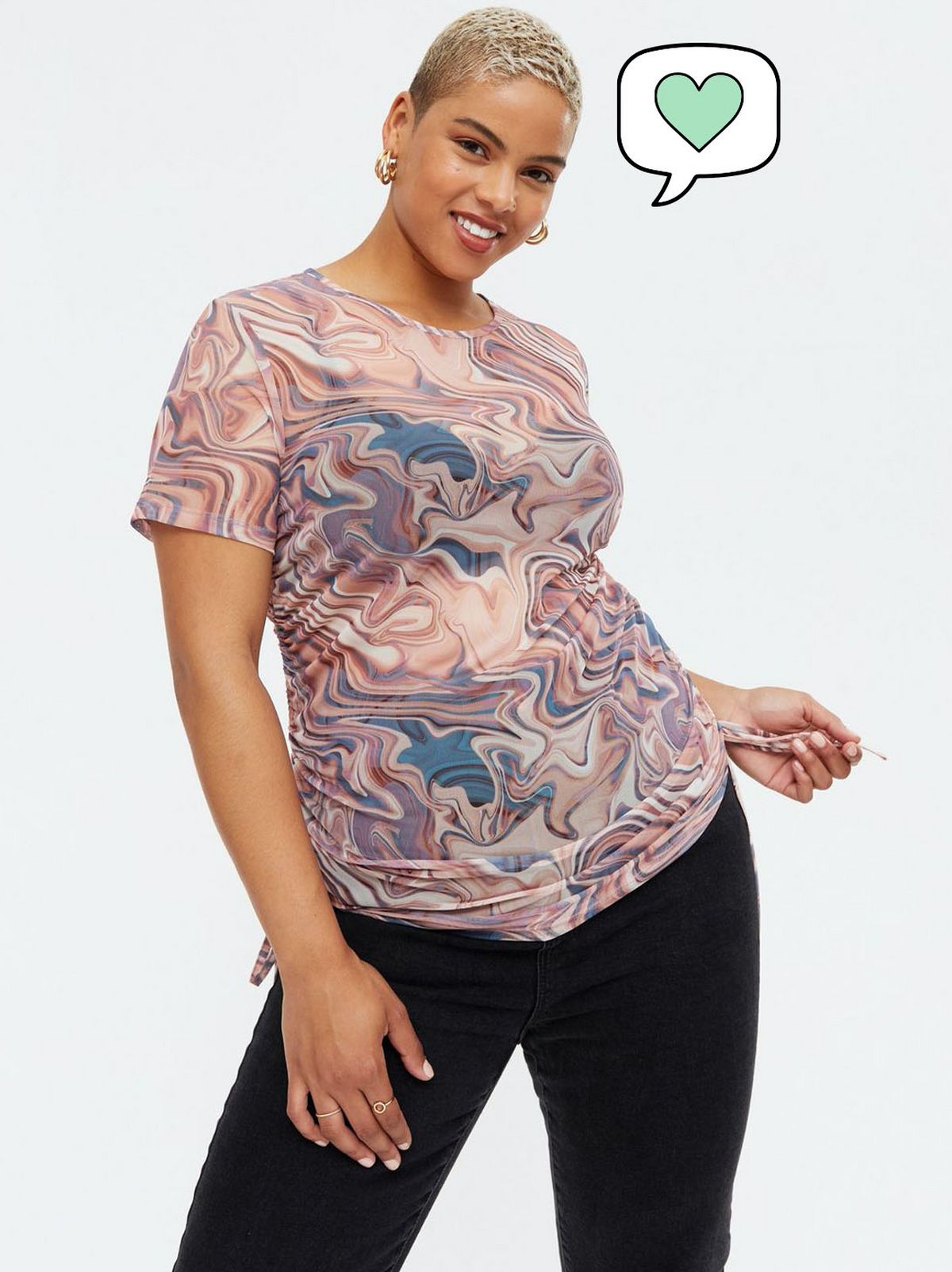 Woman wearing a brown marble print ruched side mesh top and black trousers