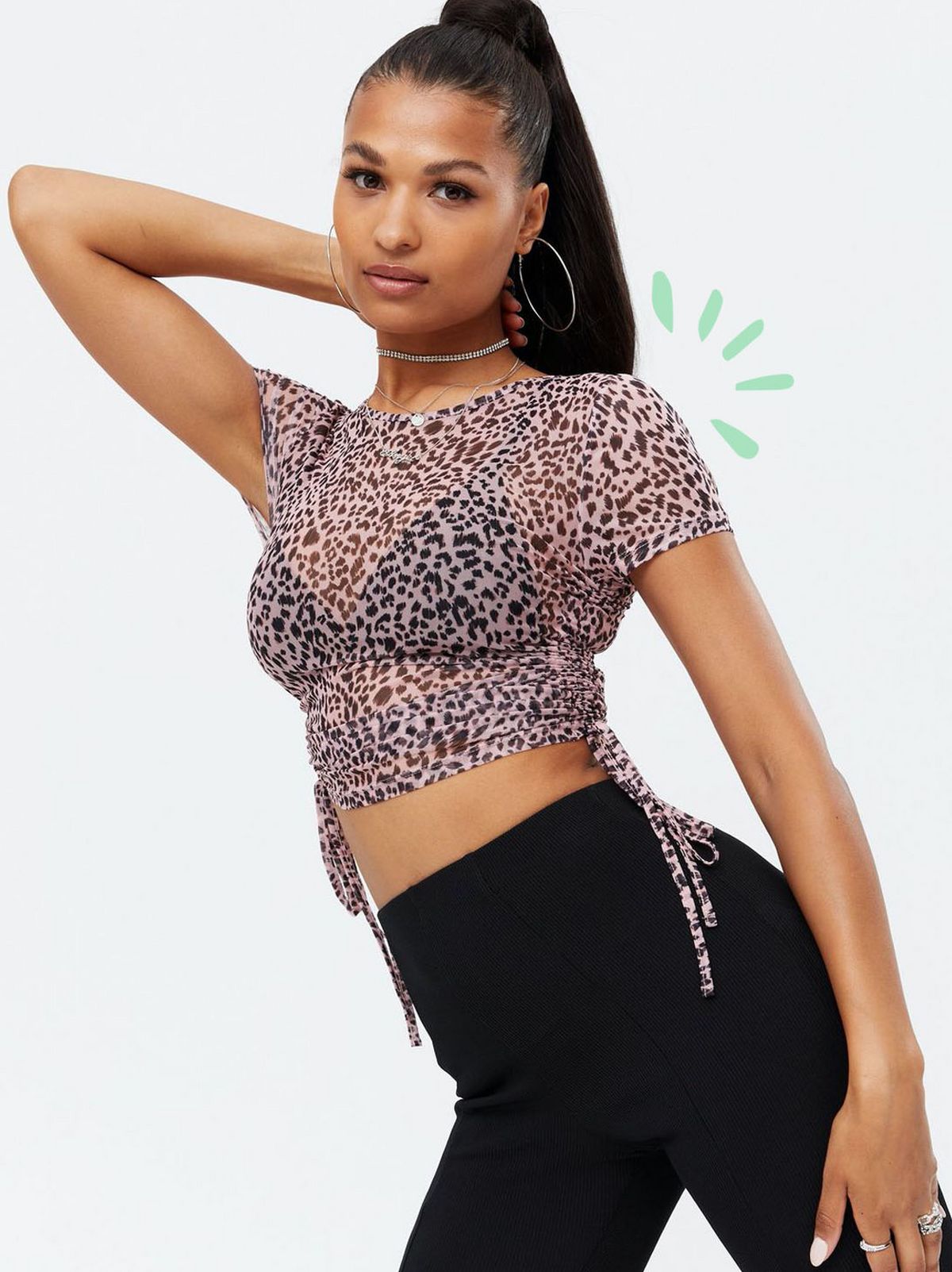 Woman wearing a pink leopard print mesh crop t-shirt and black trousers