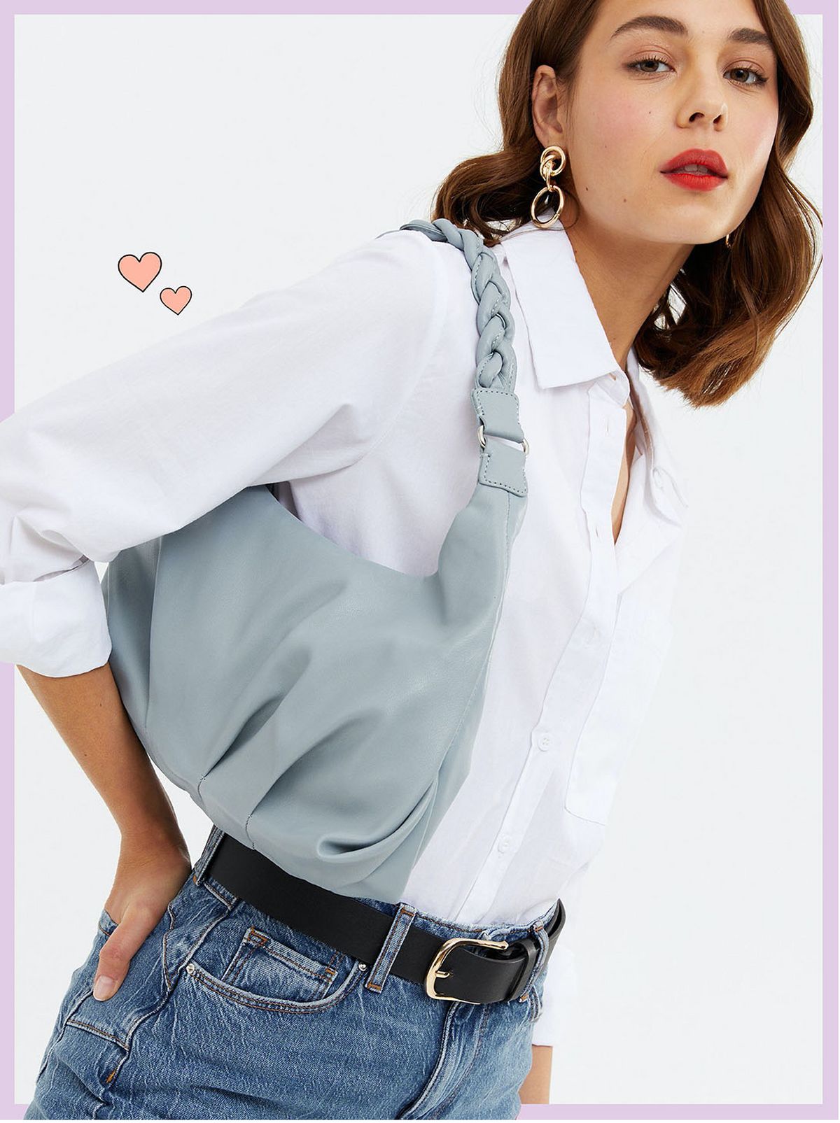 Woman carrying a blue leather look plaited strap shoulder bag wearing a white shirt and jeans