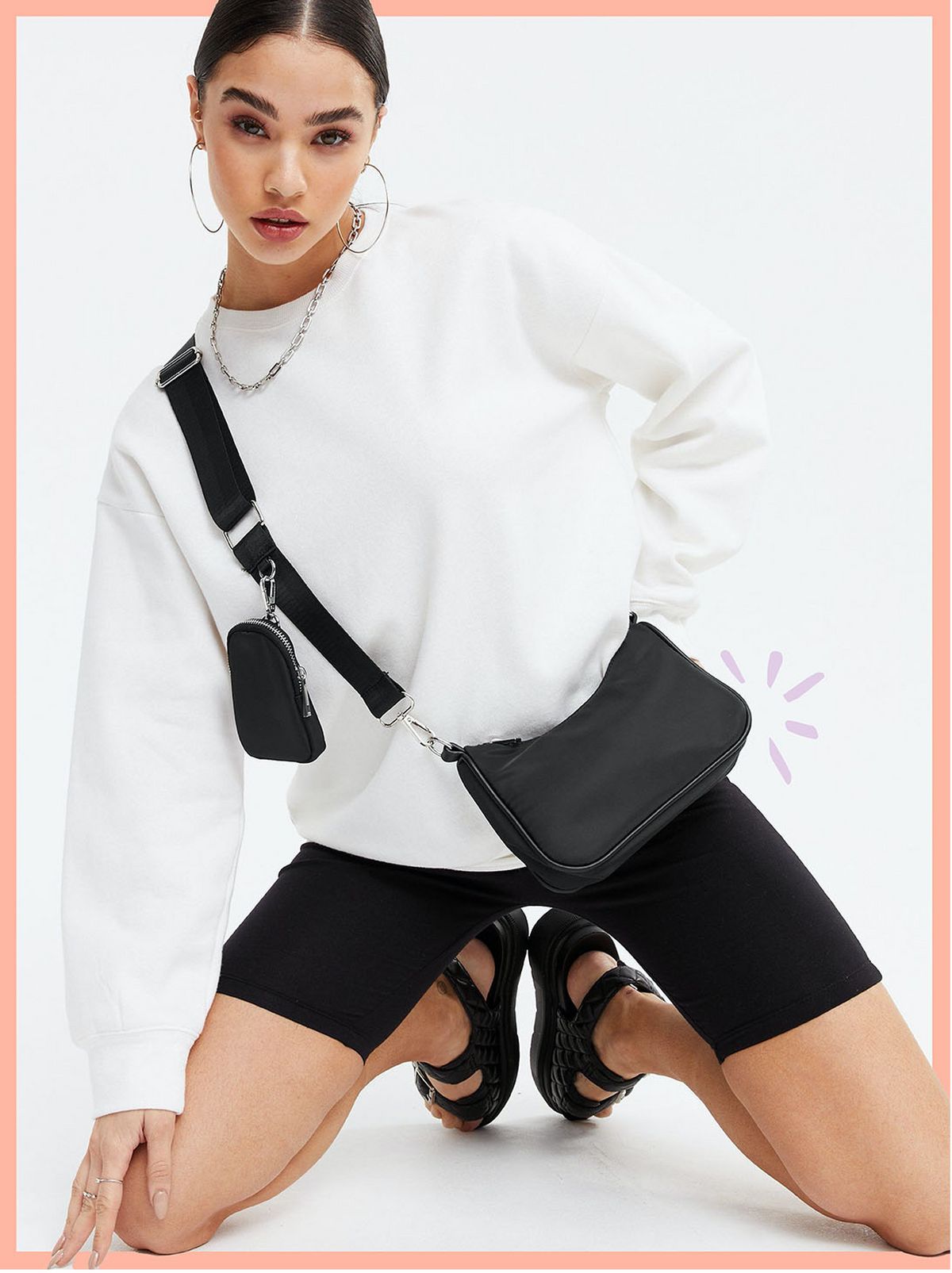 Woman carrying a black cross body bag wearing a white jumper, cycling shorts and black sandals