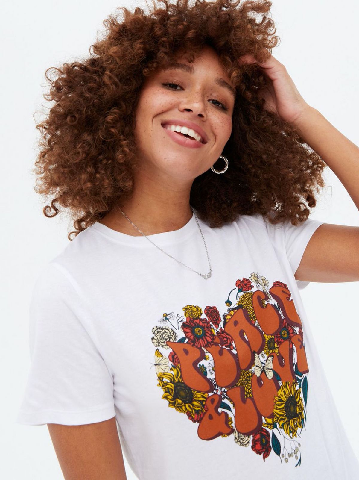 Woman wearing a white heart flower peace and love logo t-shirt