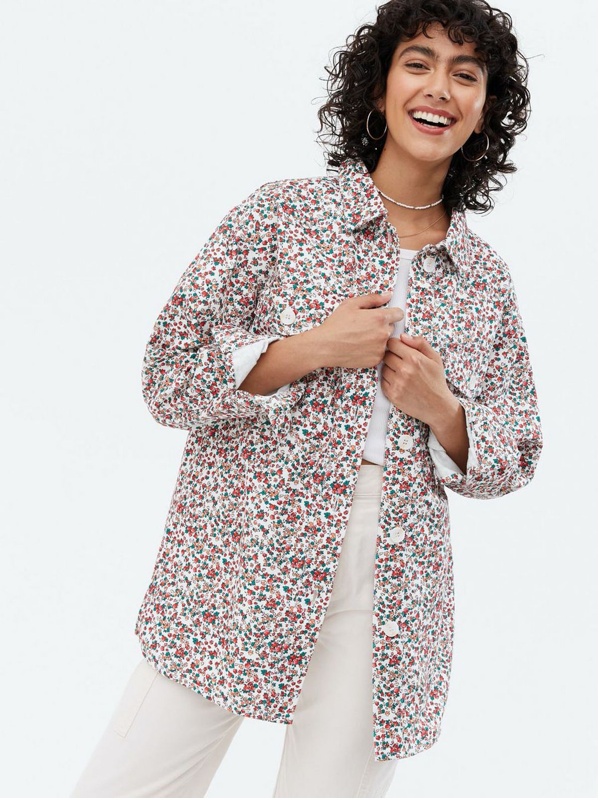 Woman wearing a white ditsy floral cotton shacket, white top and trousers