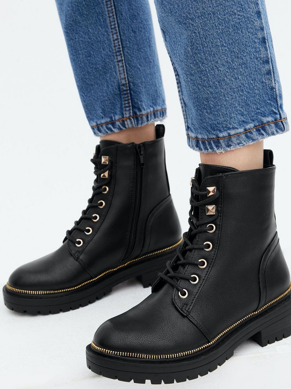 Woman wearing black leather look chunky boots and blue jeans