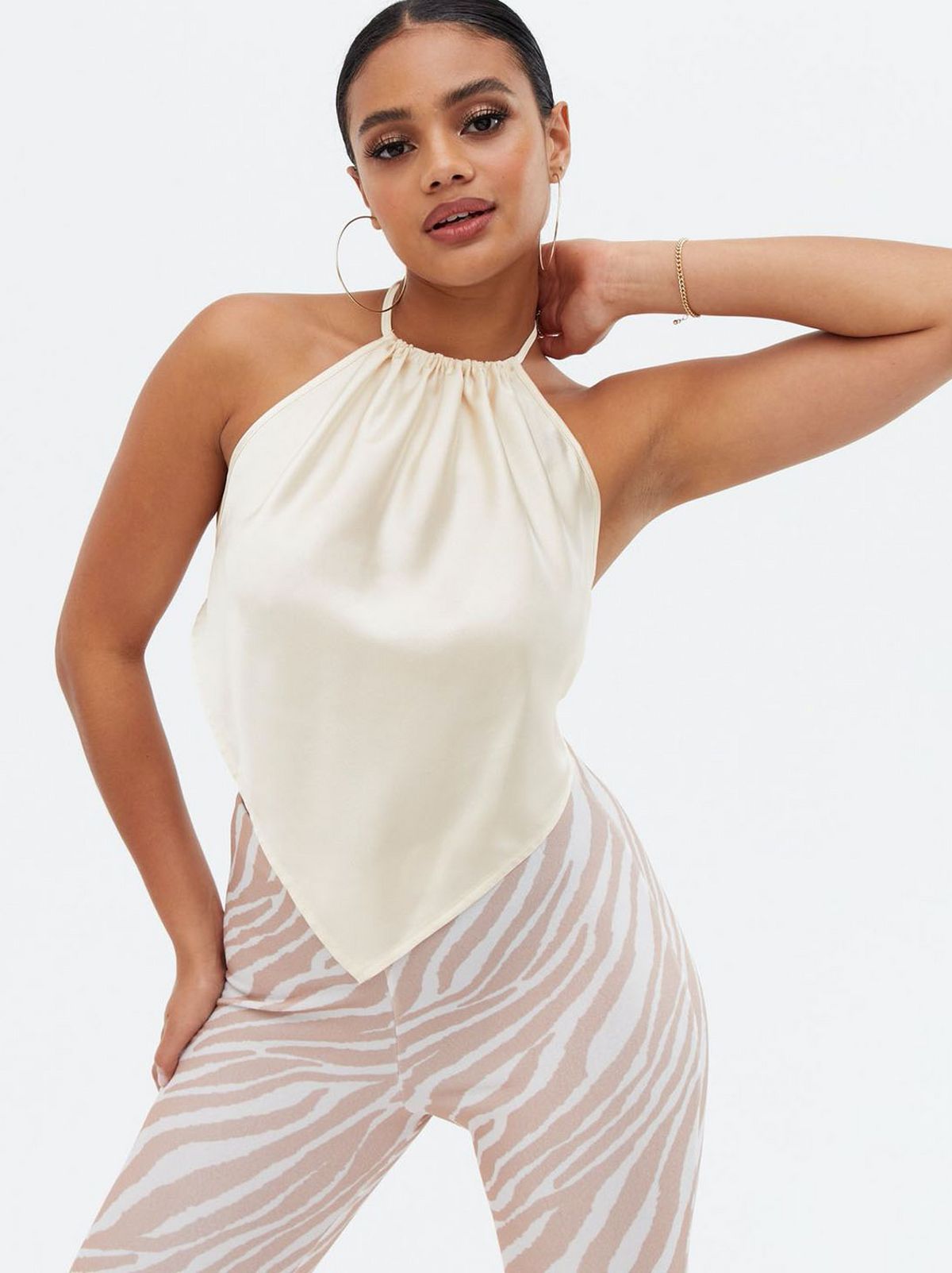 Woman wearing a cream satin hanky hem halter top and zebra print trousers