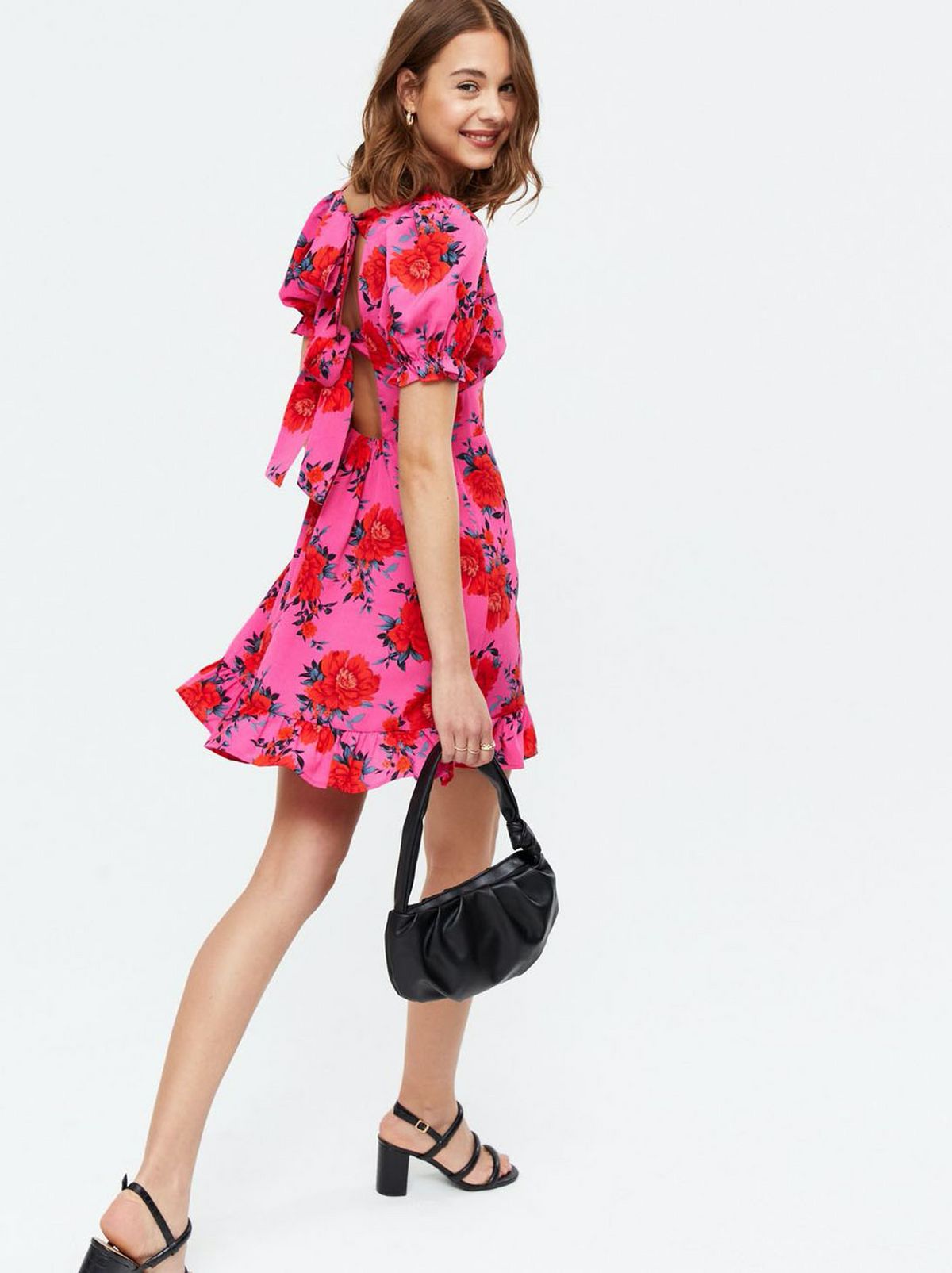 Woman wearing a pink floral puff sleeve mini dress and black heels