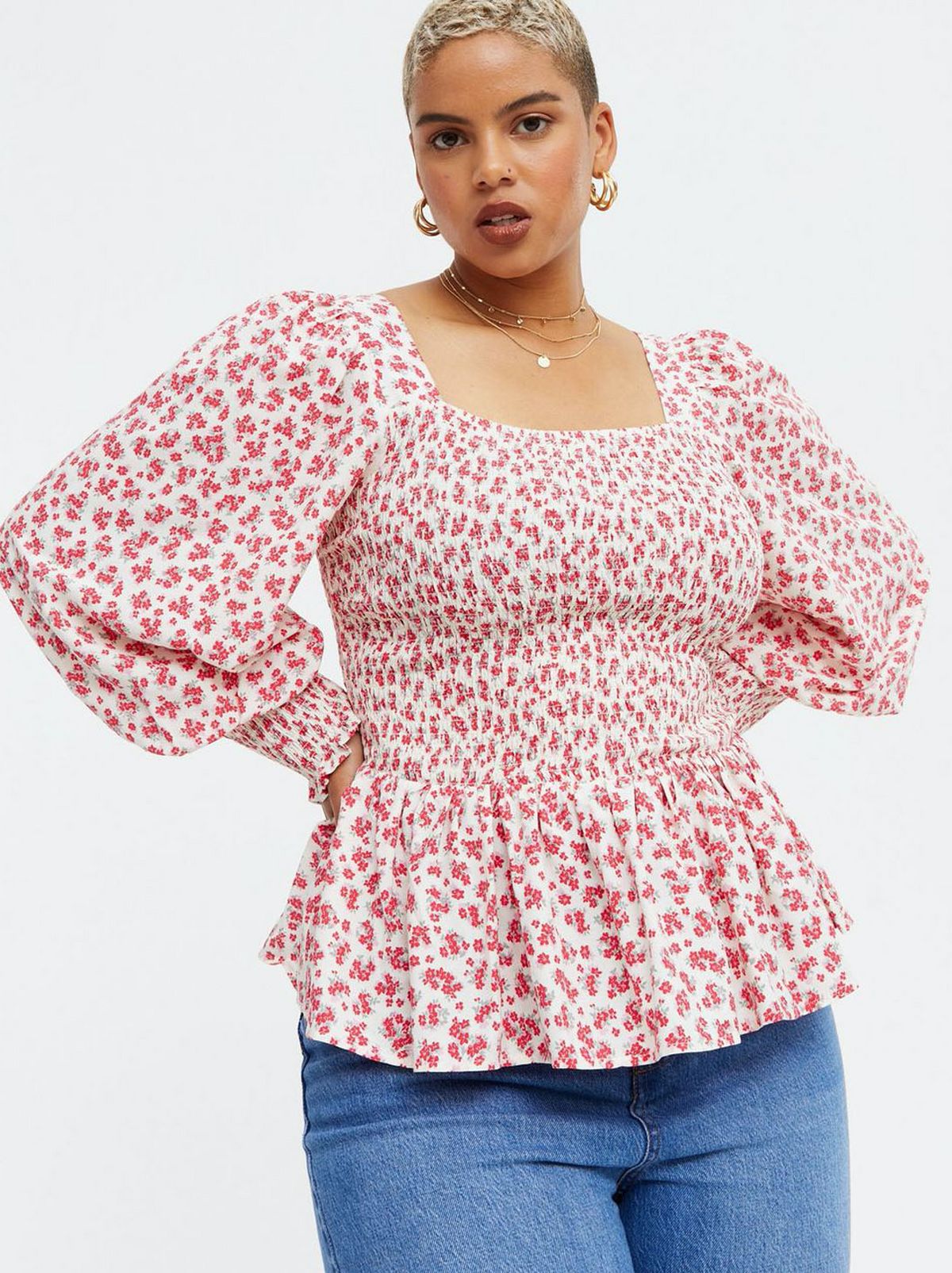Woman wearing a floral shirred square neck peplum top and blue jeans