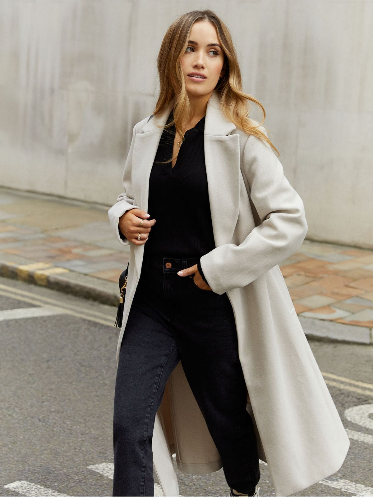Kate Hutchins New Look Ambassador wearing a long cream coat, black jeans and shirt