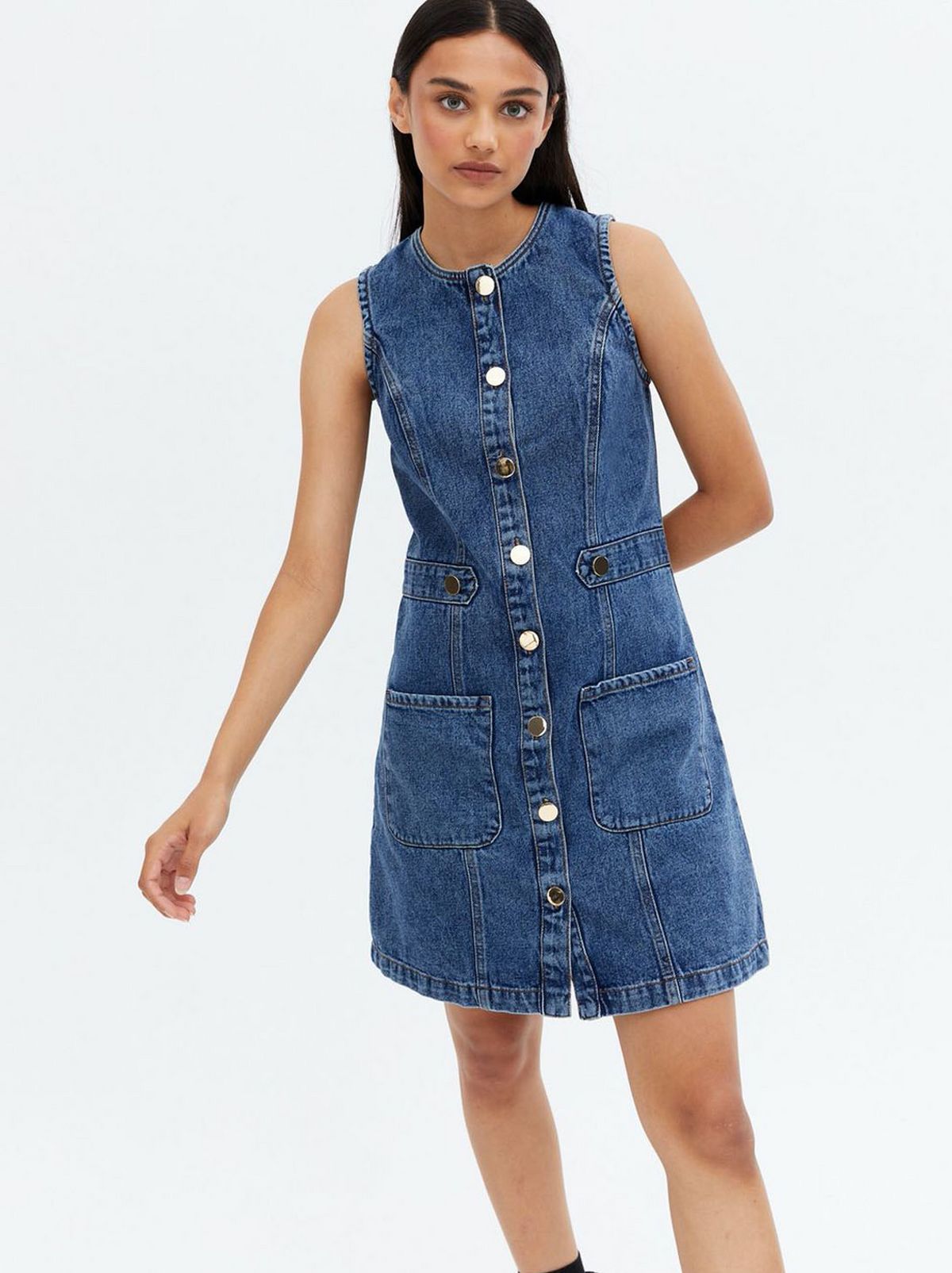 Woman wearing a blue denim button mini pinafore dress