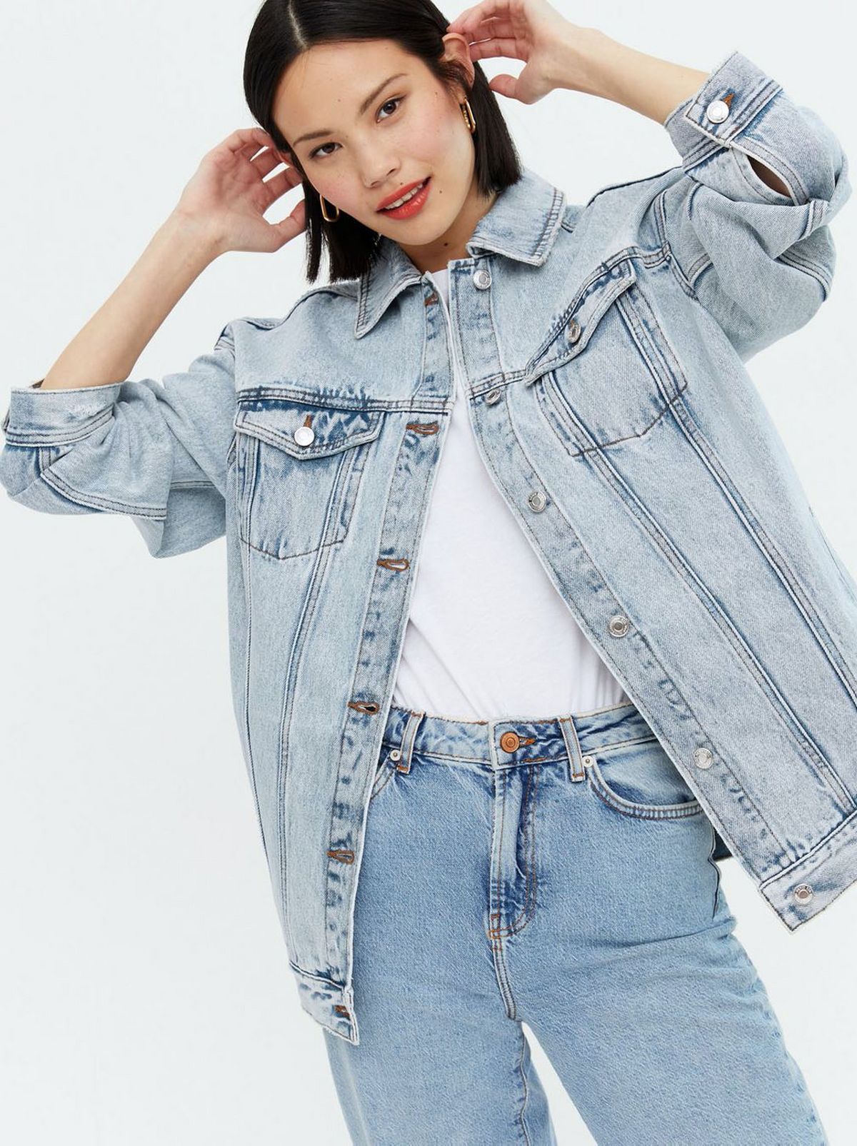 Woman wearing a blue oversized denim jacket, white shirt and blue jeans