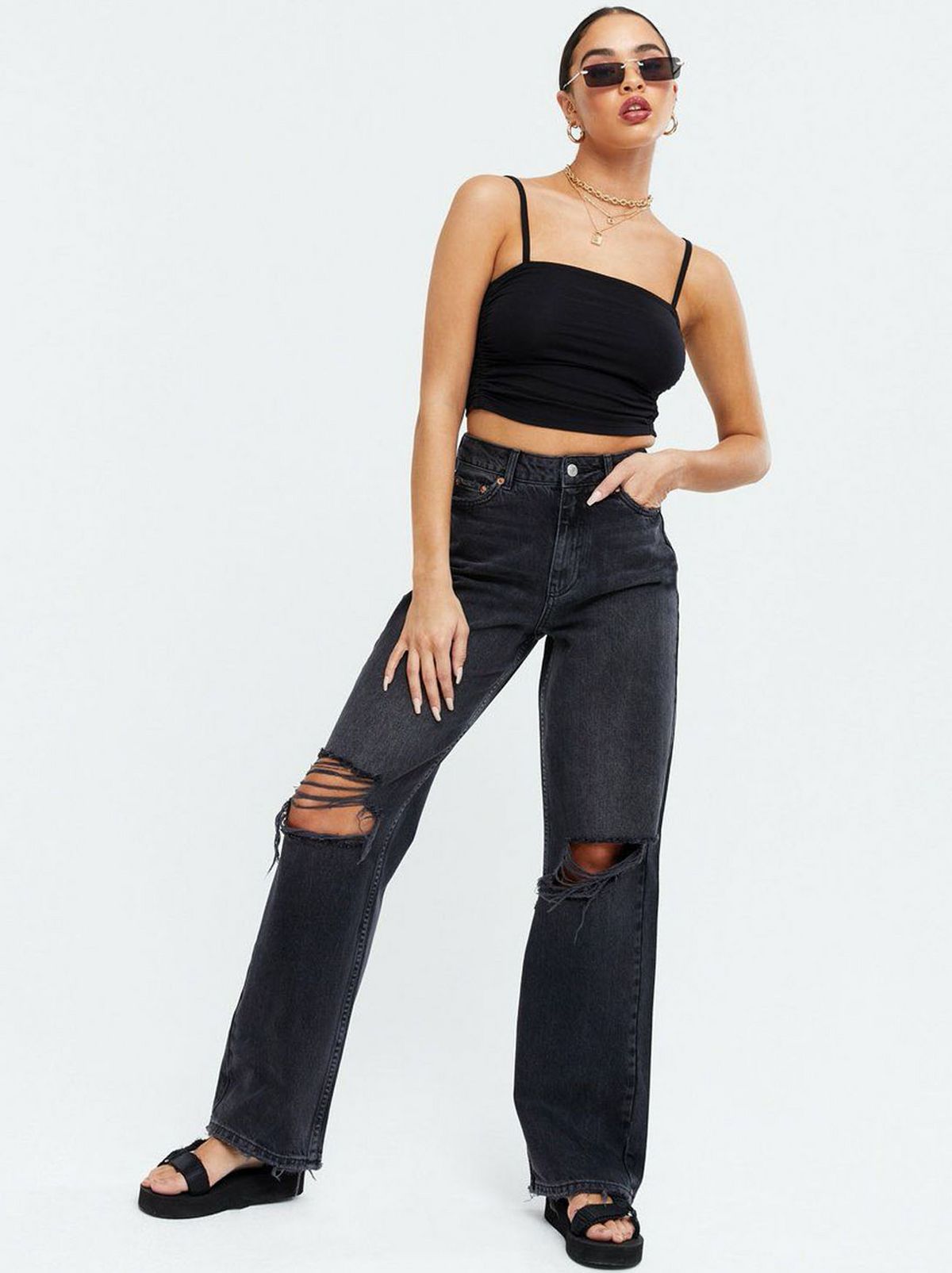Woman wearing black ripped baggy fit jeans, cami top, sandals and sunglasses