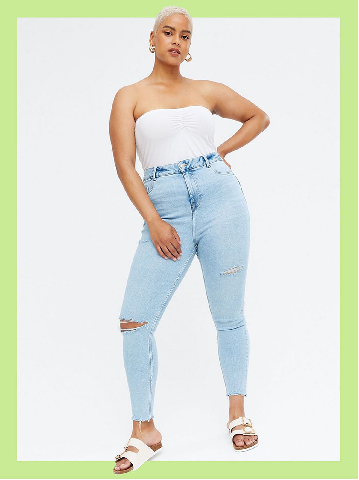 Woman wearing pale blue ripped high waist super skinny jeans, white top and sandals